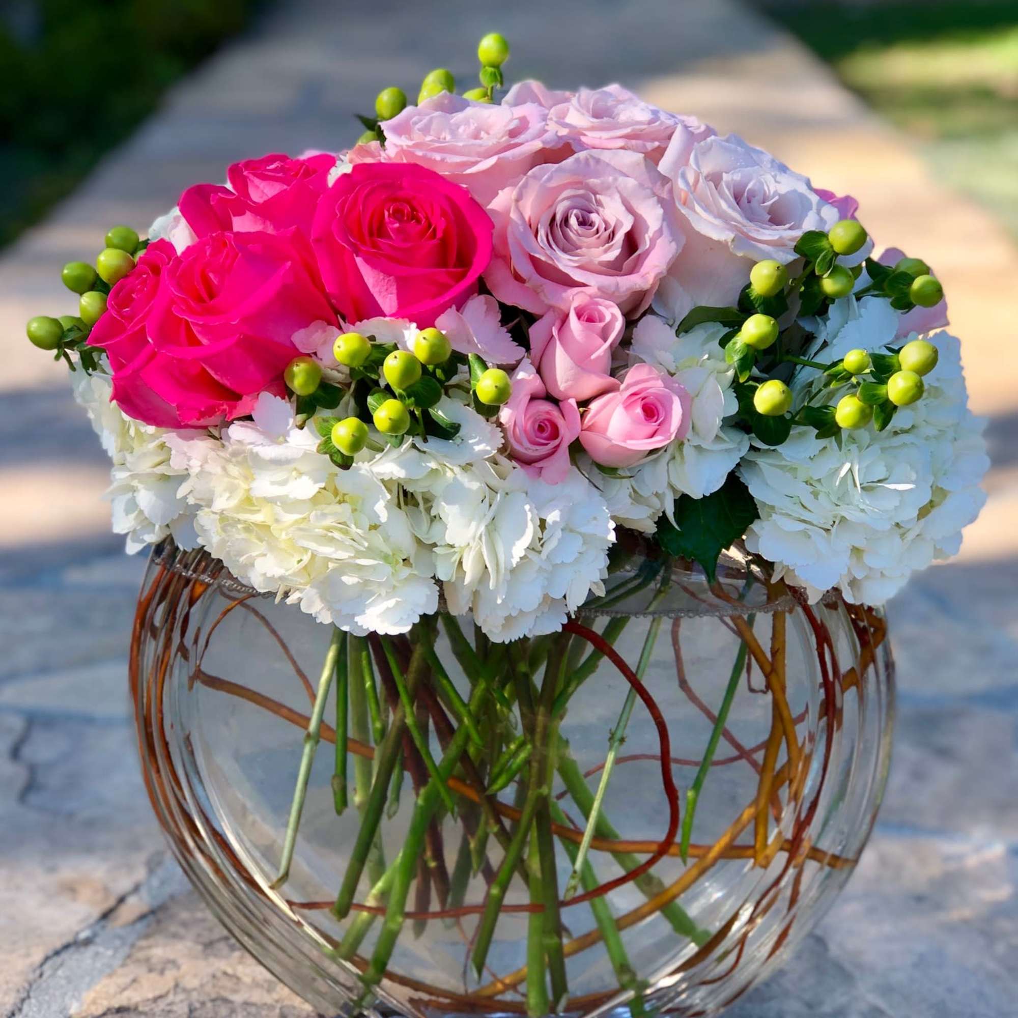 Pink and white roses in a round glass vase