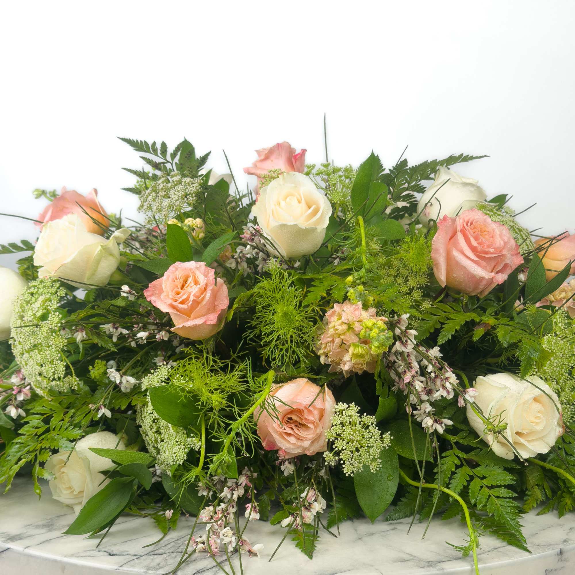 Low bouquet of blush and white roses with mixed greenery
