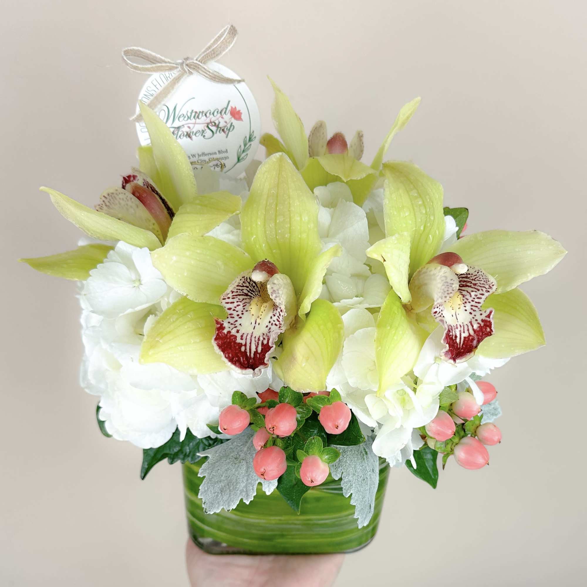 White and lime-green orchid arrangement in a green glass vase