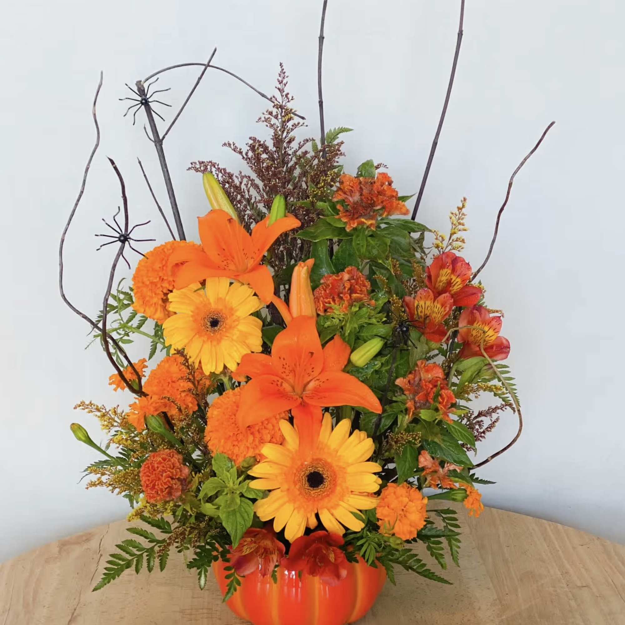 Orange and yellow floral arrangement in a pumpkin-shaped vase