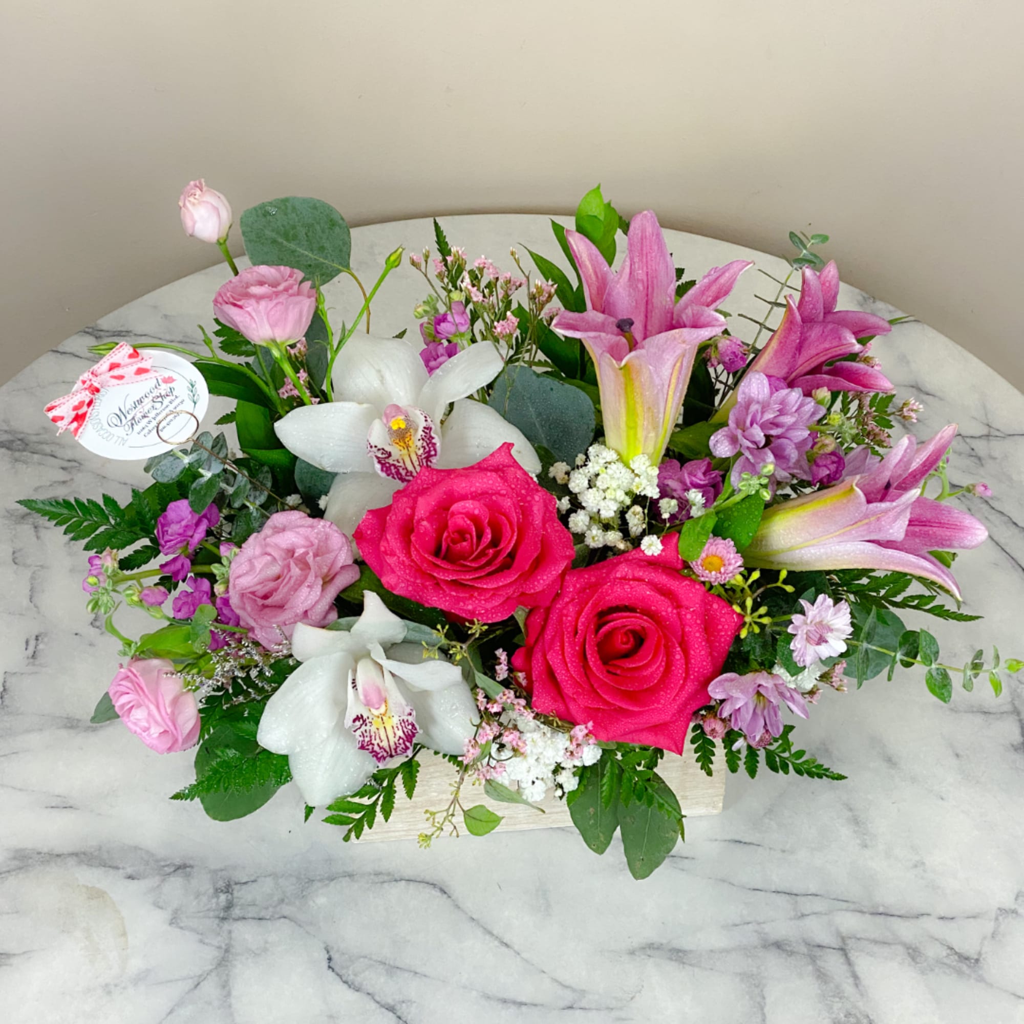 Pink roses and white orchids arranged in a low rectangular box