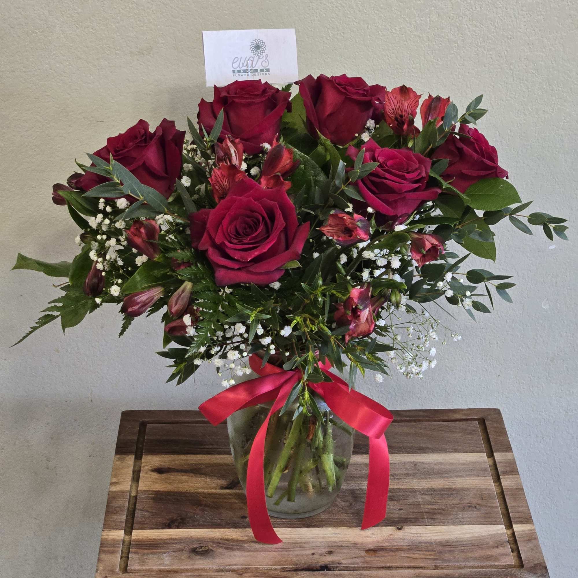 Bouquet of deep red roses and pink alstroemeria in a glass vase with a ribbon
