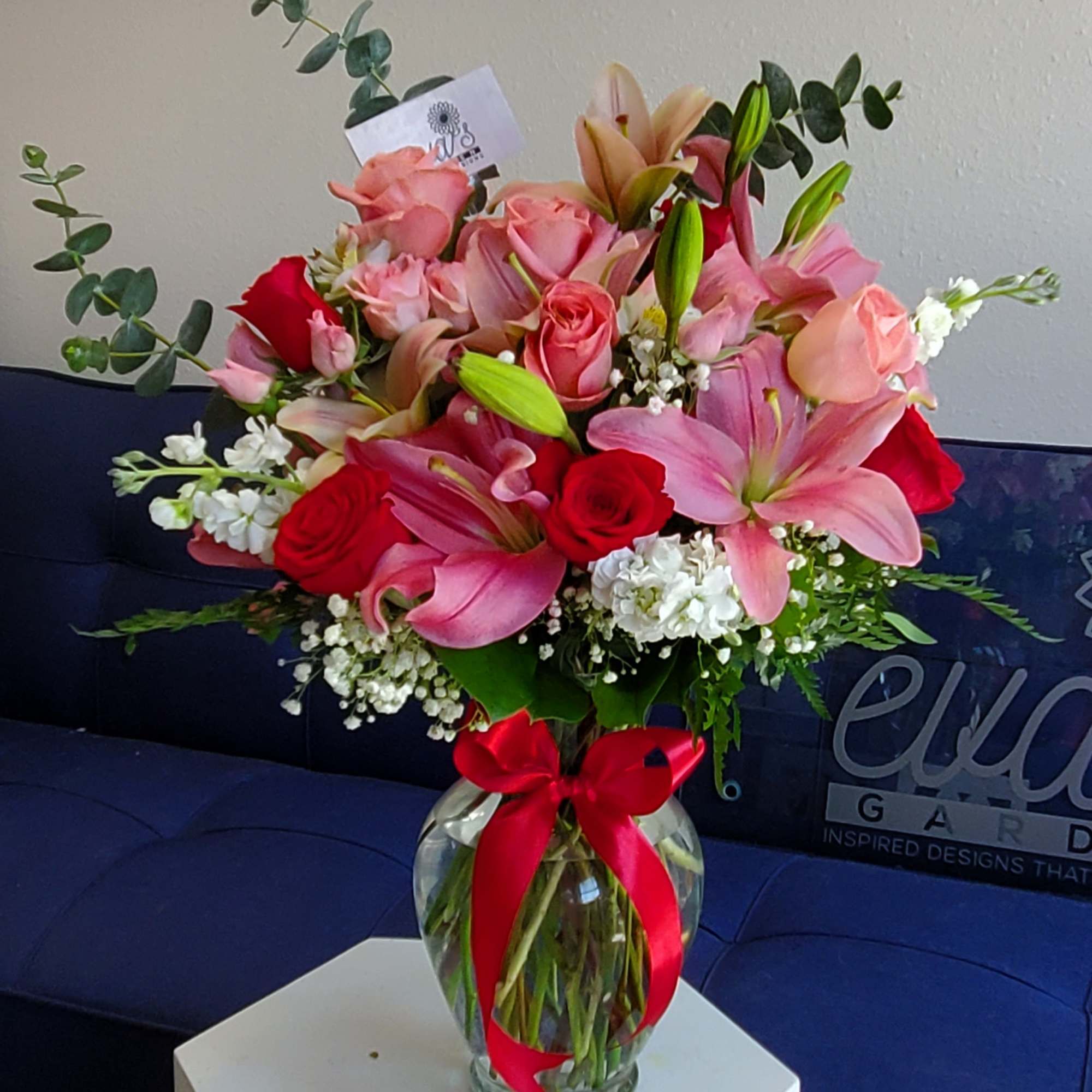 Pink and red mixed bouquet in a glass vase with a red ribbon