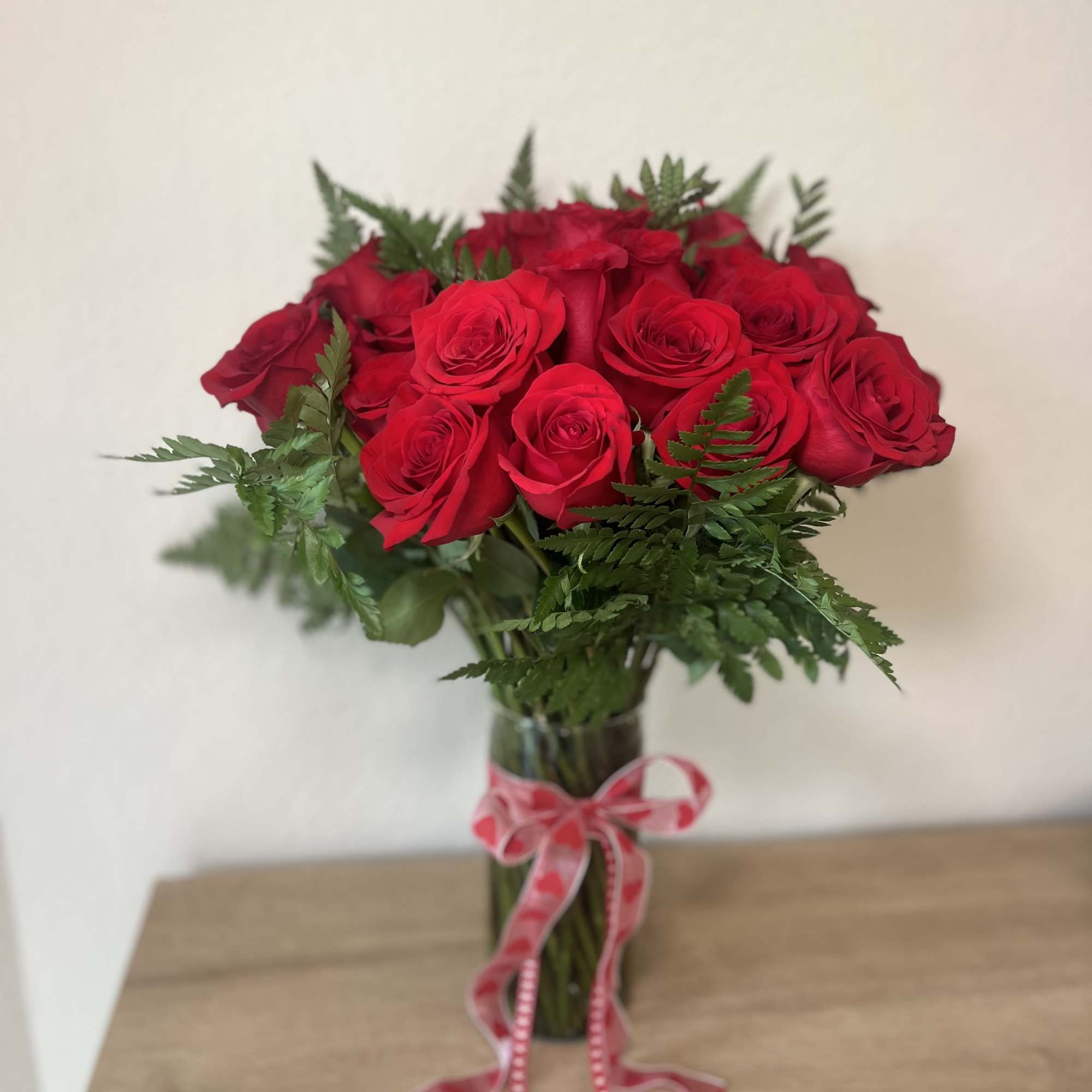 Bouquet of red roses in a glass vase with a pink ribbon