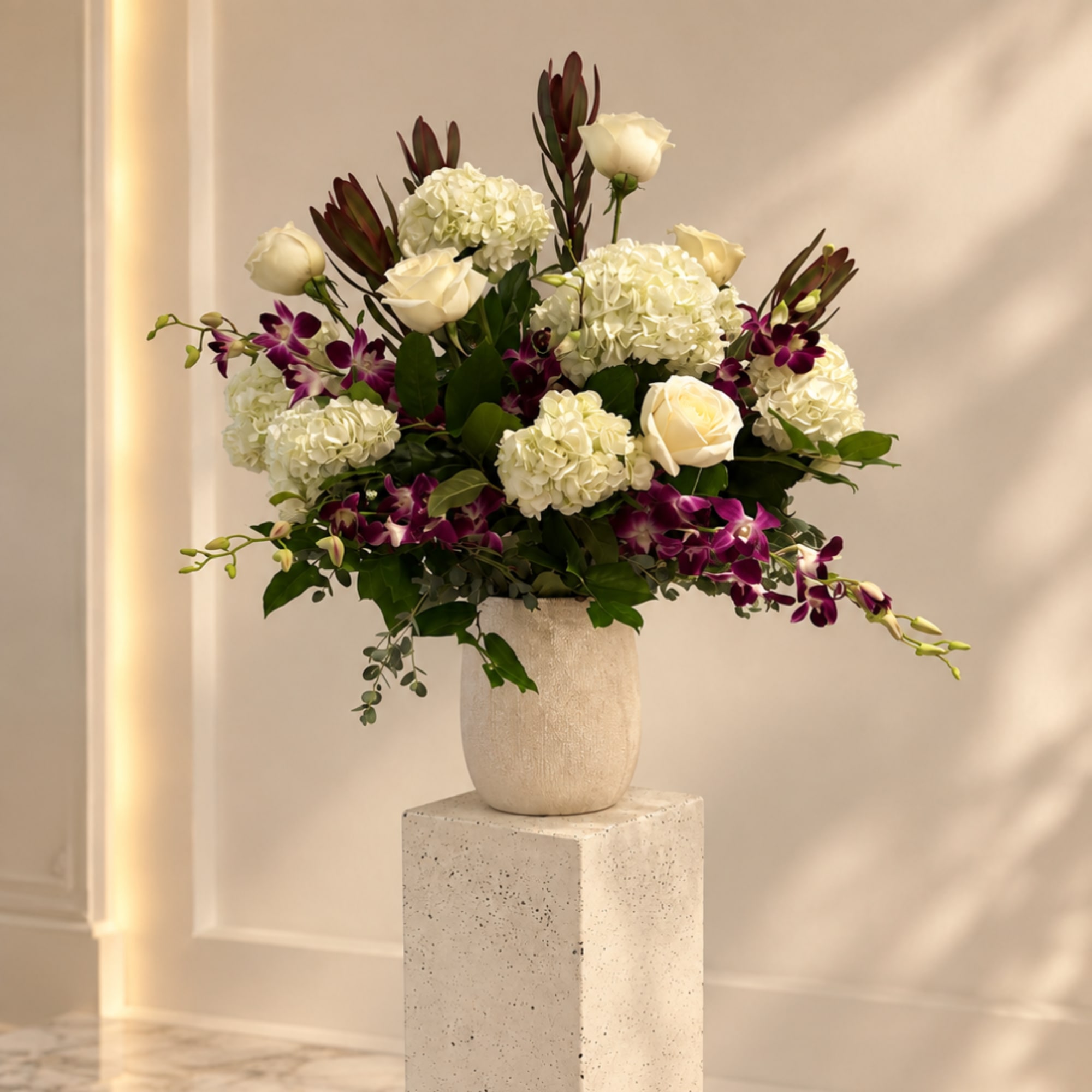 White roses and hydrangeas with purple orchids in a cream vase