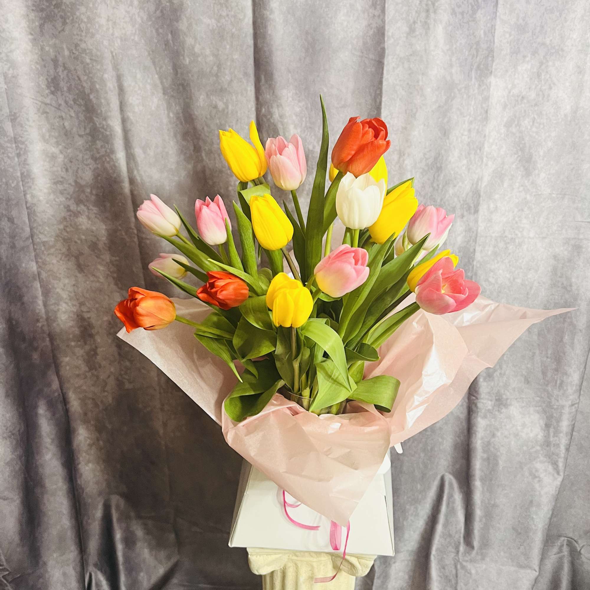 Bouquet of multicolored tulips wrapped in pale pink paper
