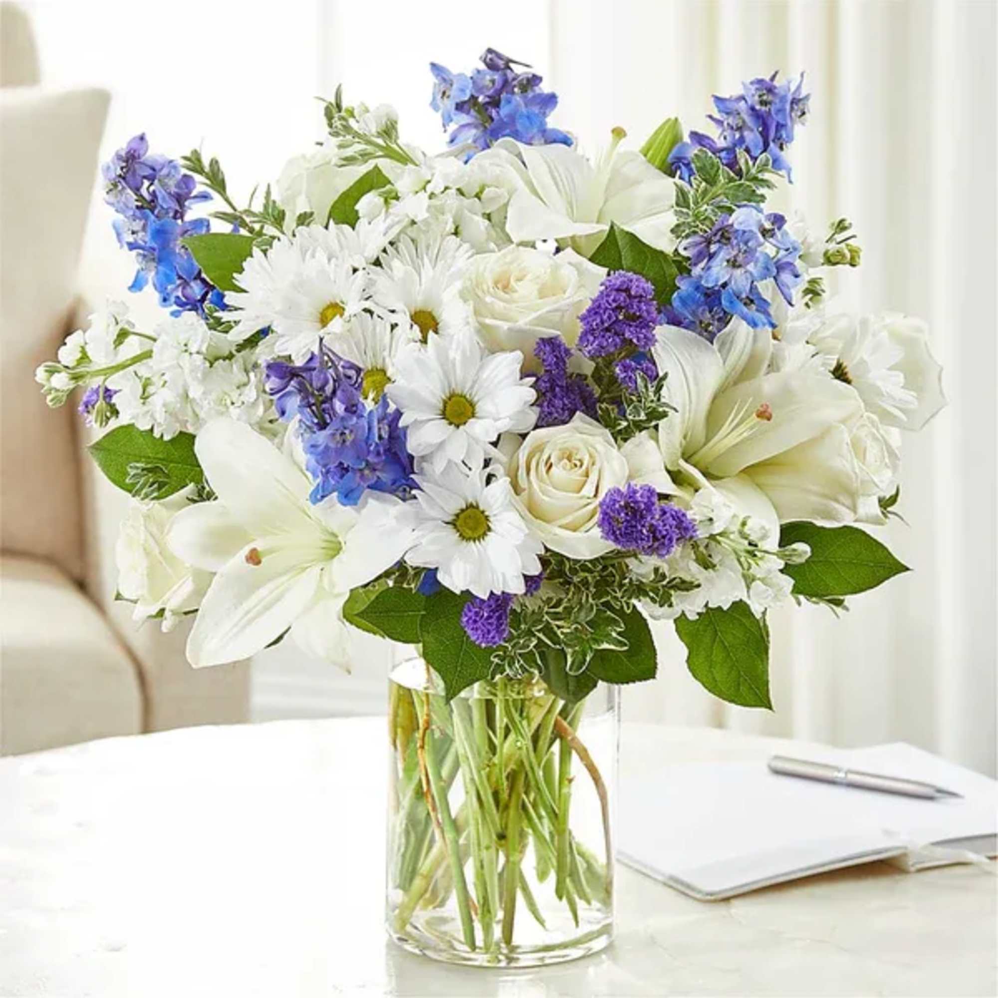 White and blue mixed bouquet in a clear glass vase