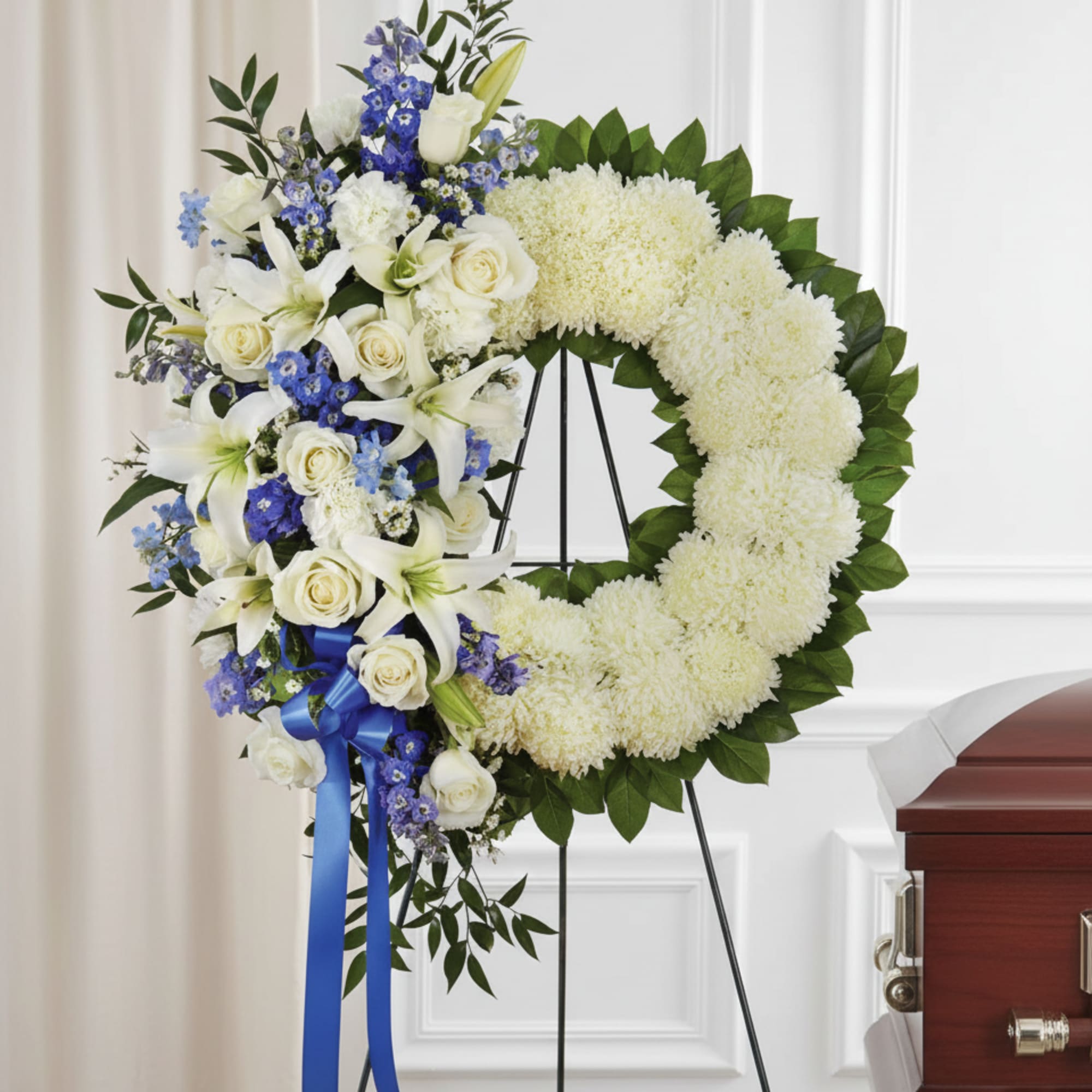 A circular wreath of pure white chrysanthemums edged with deep green foliage