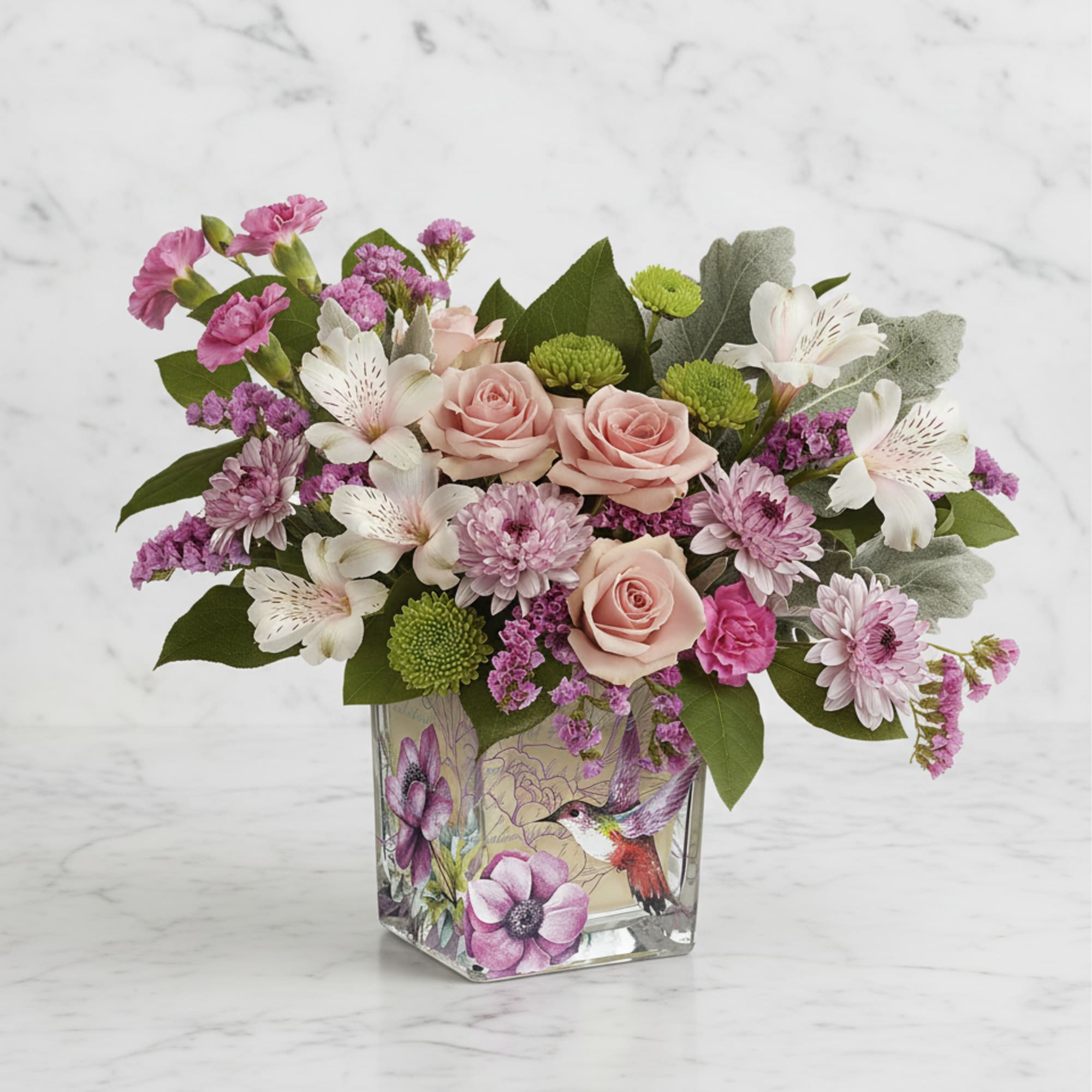 Pink roses and mixed blooms arranged in a square glass vase