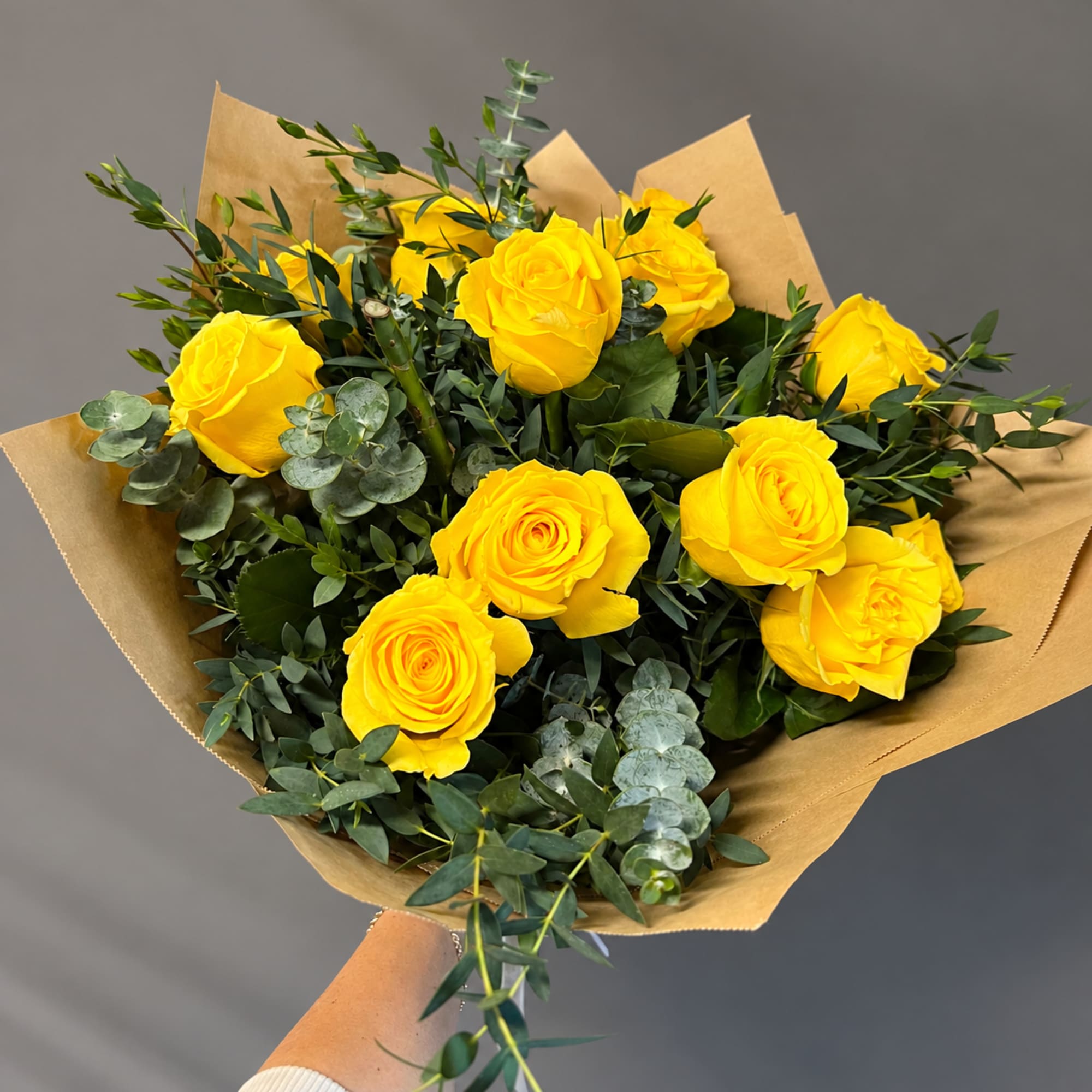 Bouquet of yellow roses wrapped in brown paper