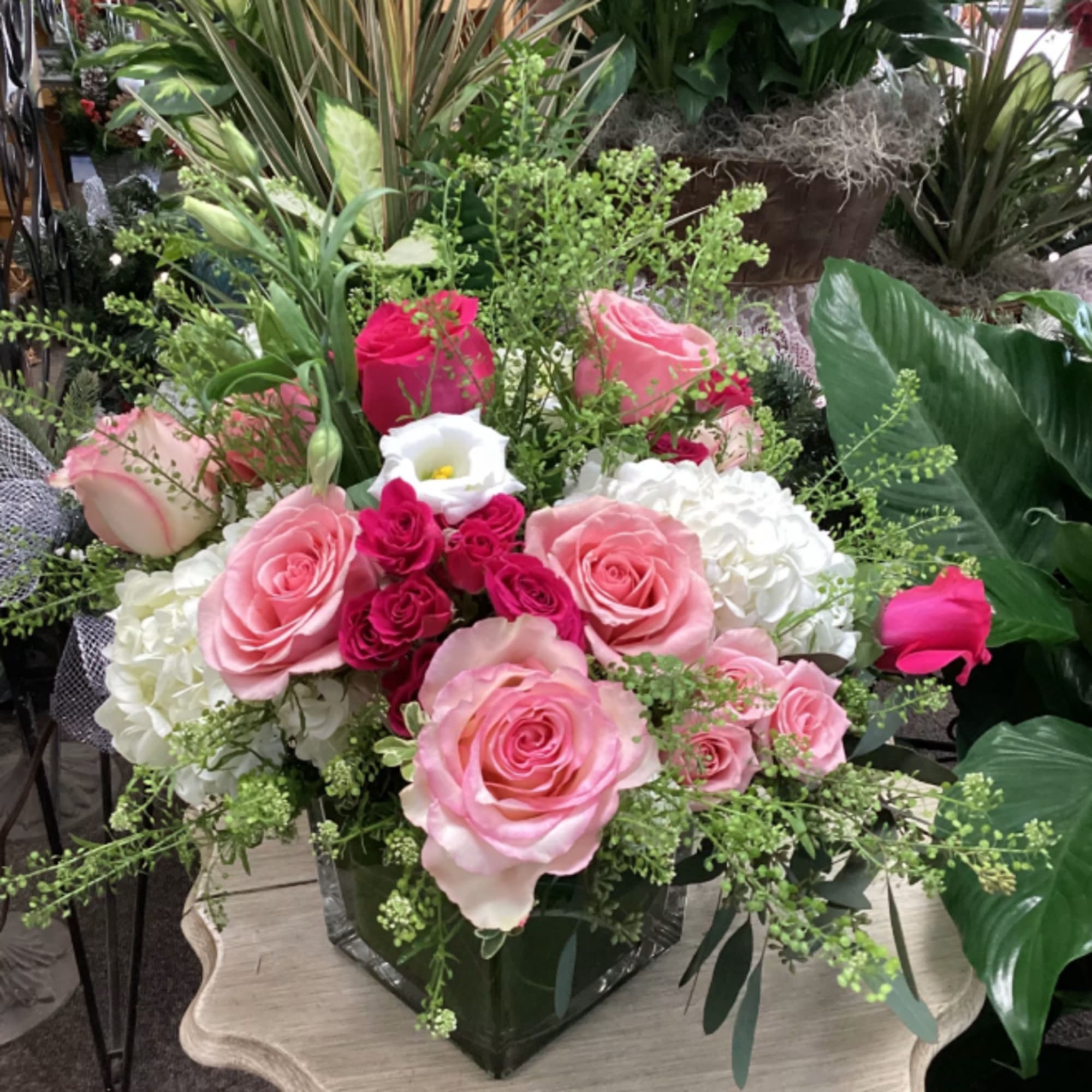 Pink and white rose arrangement with hydrangeas in a clear square glass vase