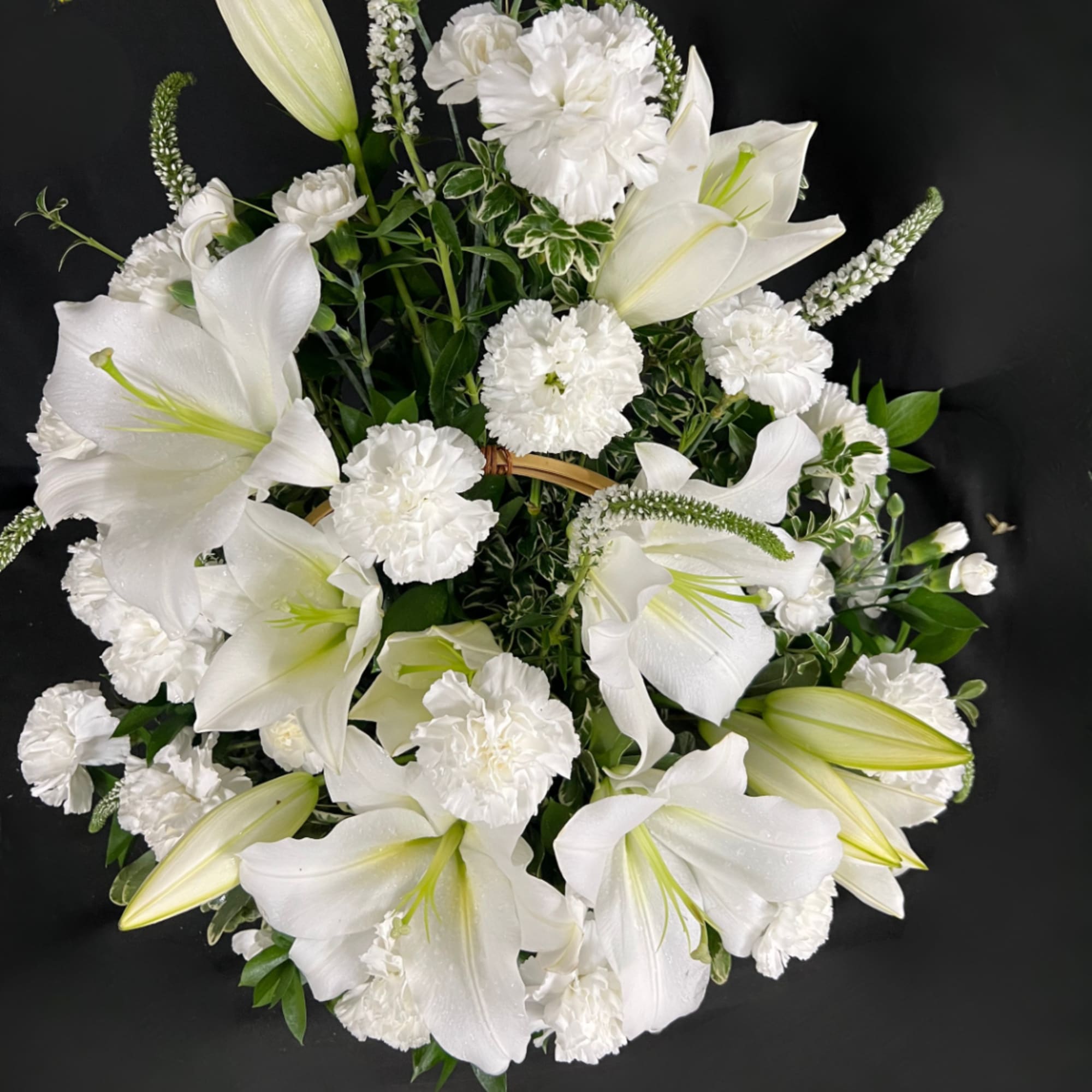 White lilies and carnations arranged in a round bouquet