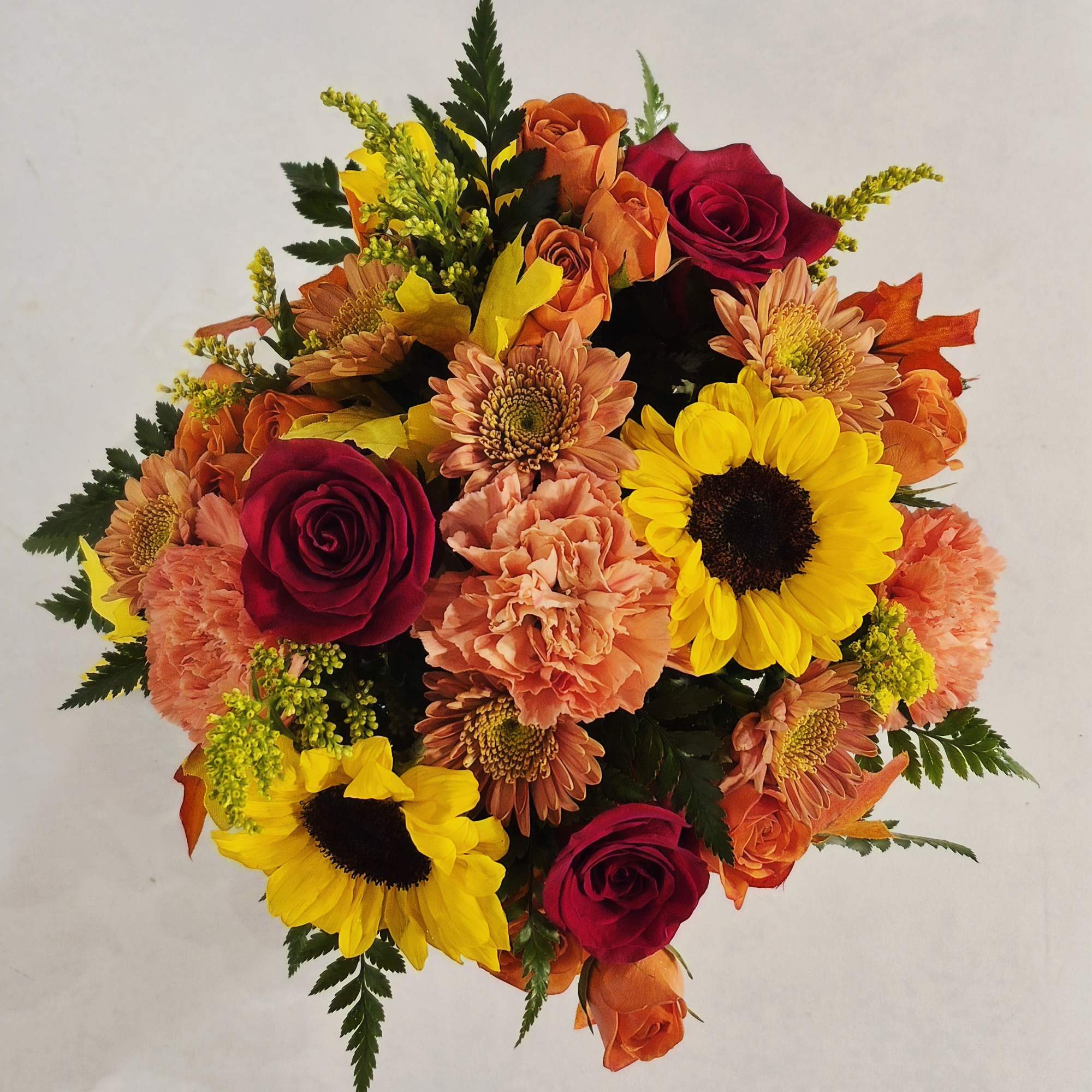 Round bouquet of red roses, sunflowers, and peach carnations