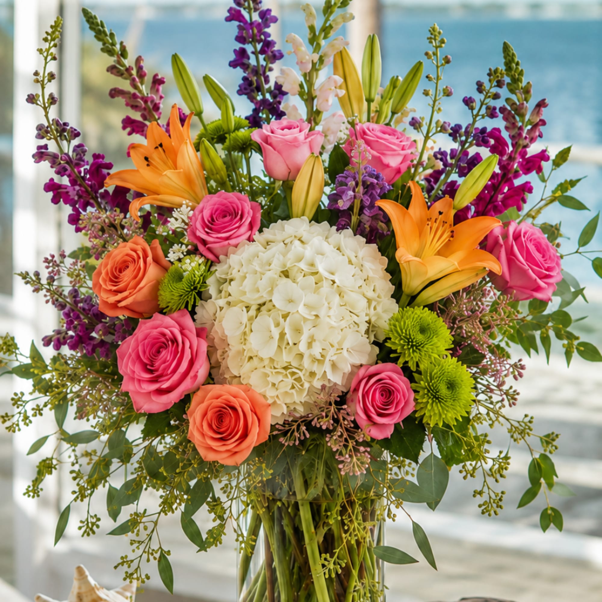 Colorful bouquet of roses, lilies, and hydrangea in a clear glass vase