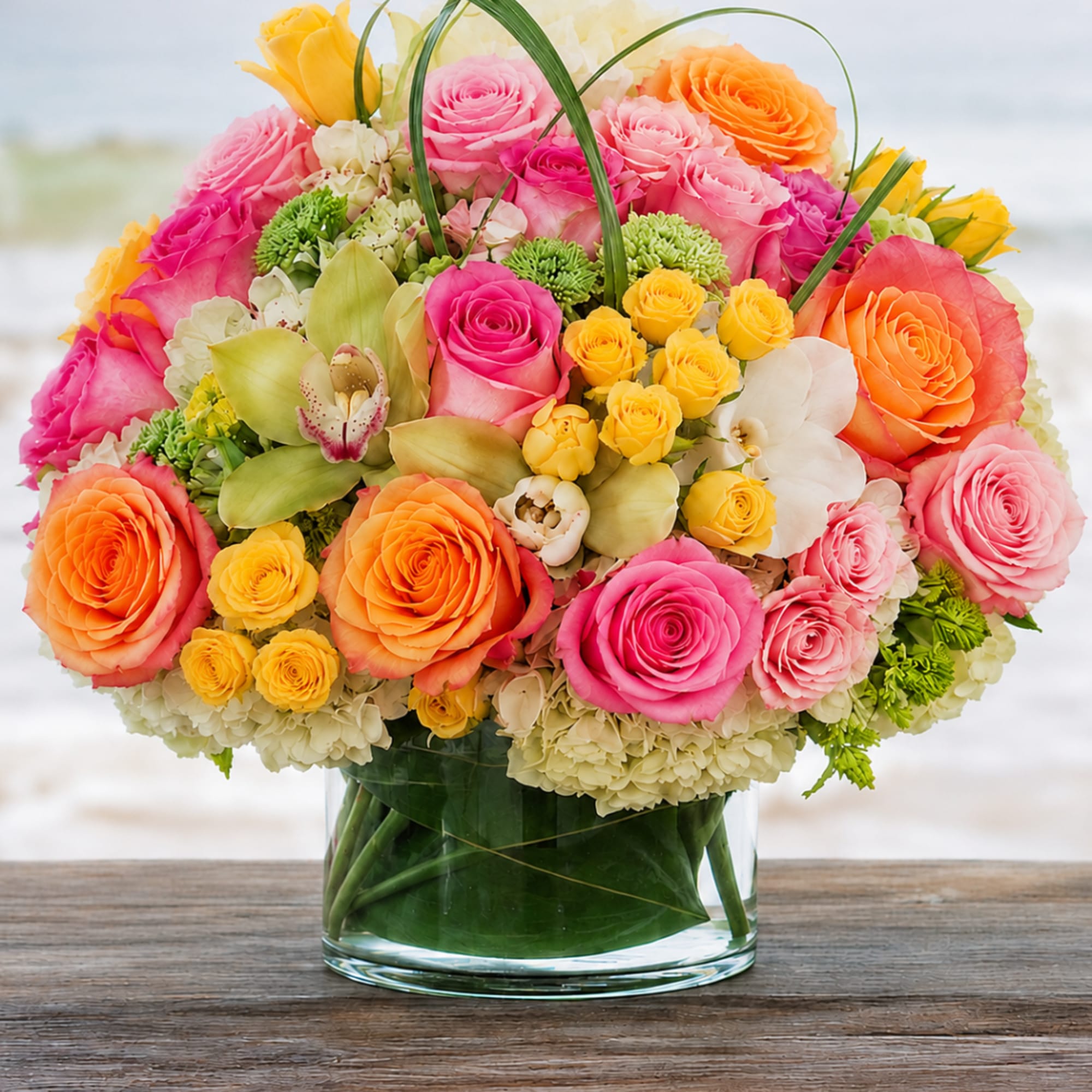 Colorful bouquet of roses and orchids in a clear glass vase
