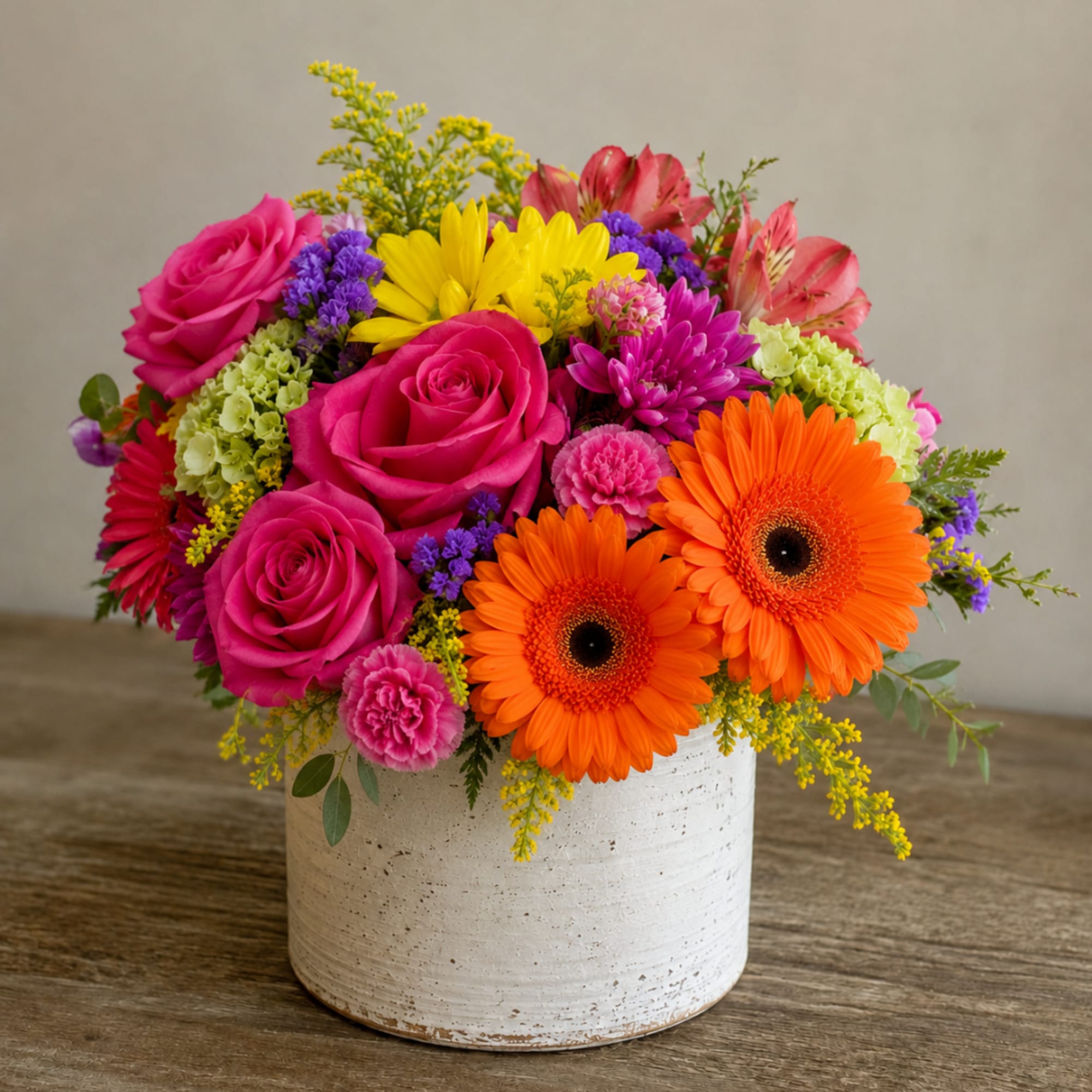 Bright mixed bouquet in a white ceramic vase with roses and gerbera daisies