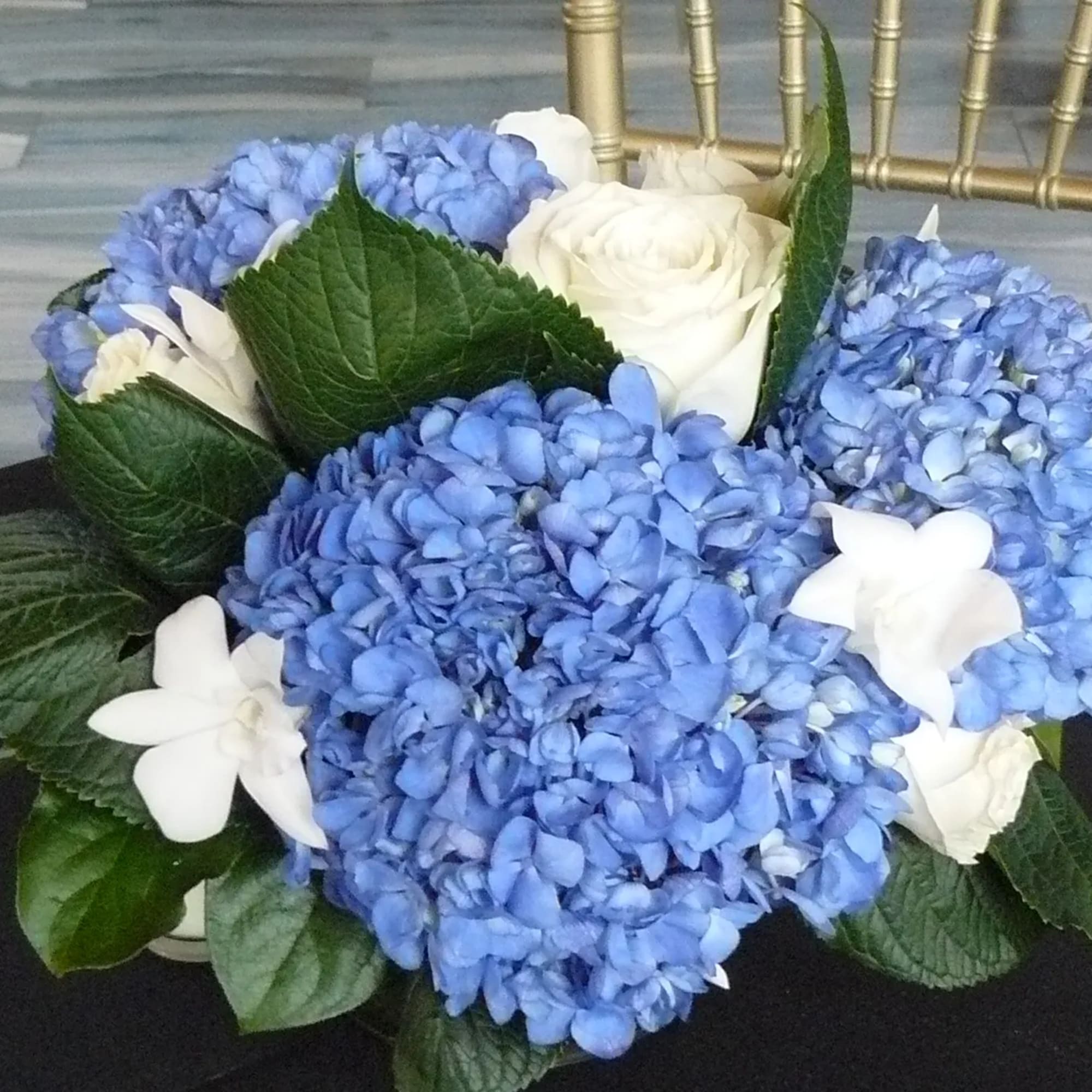 Blue hydrangea and white rose arrangement on a dark table