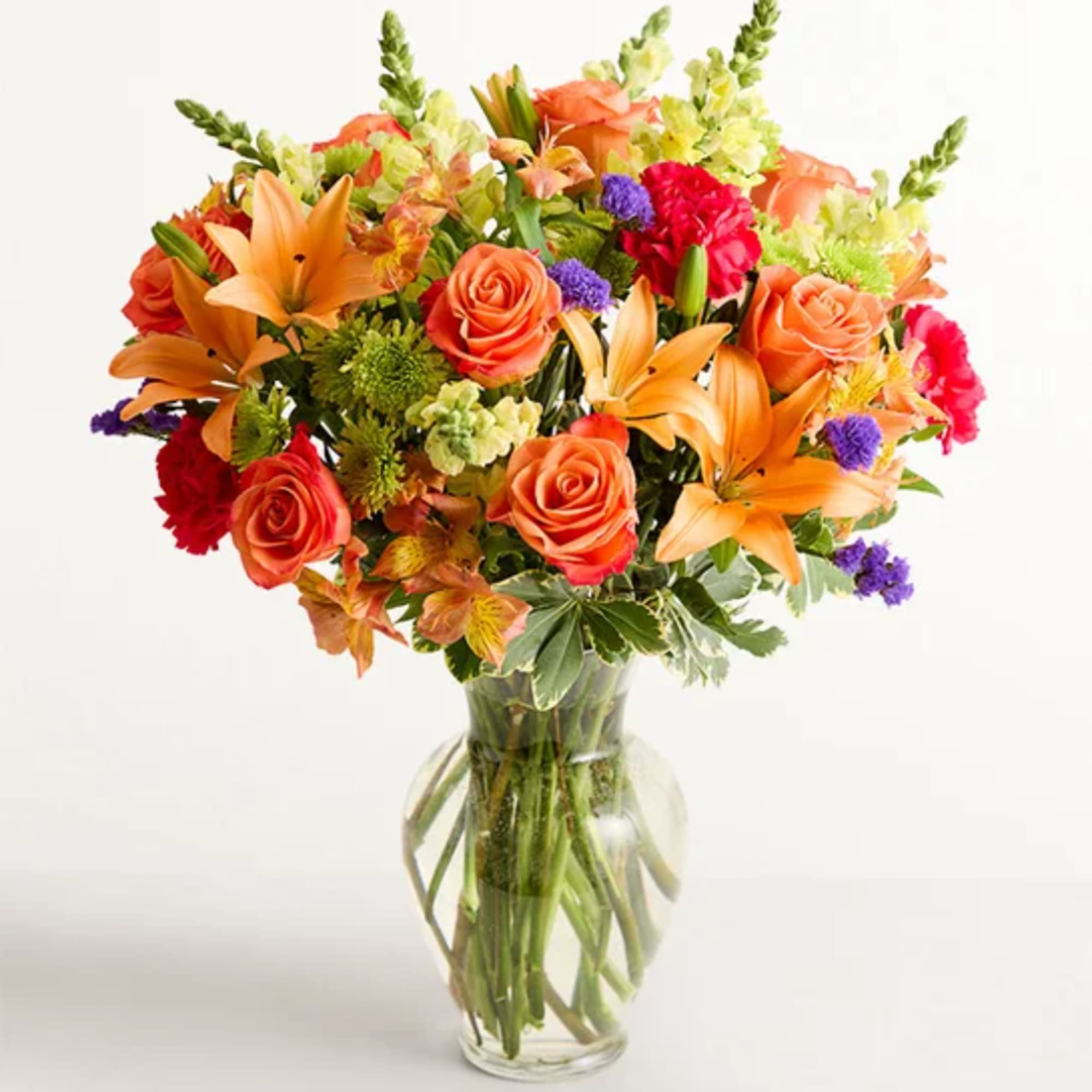 Mixed bouquet of orange roses and lilies in a clear glass vase