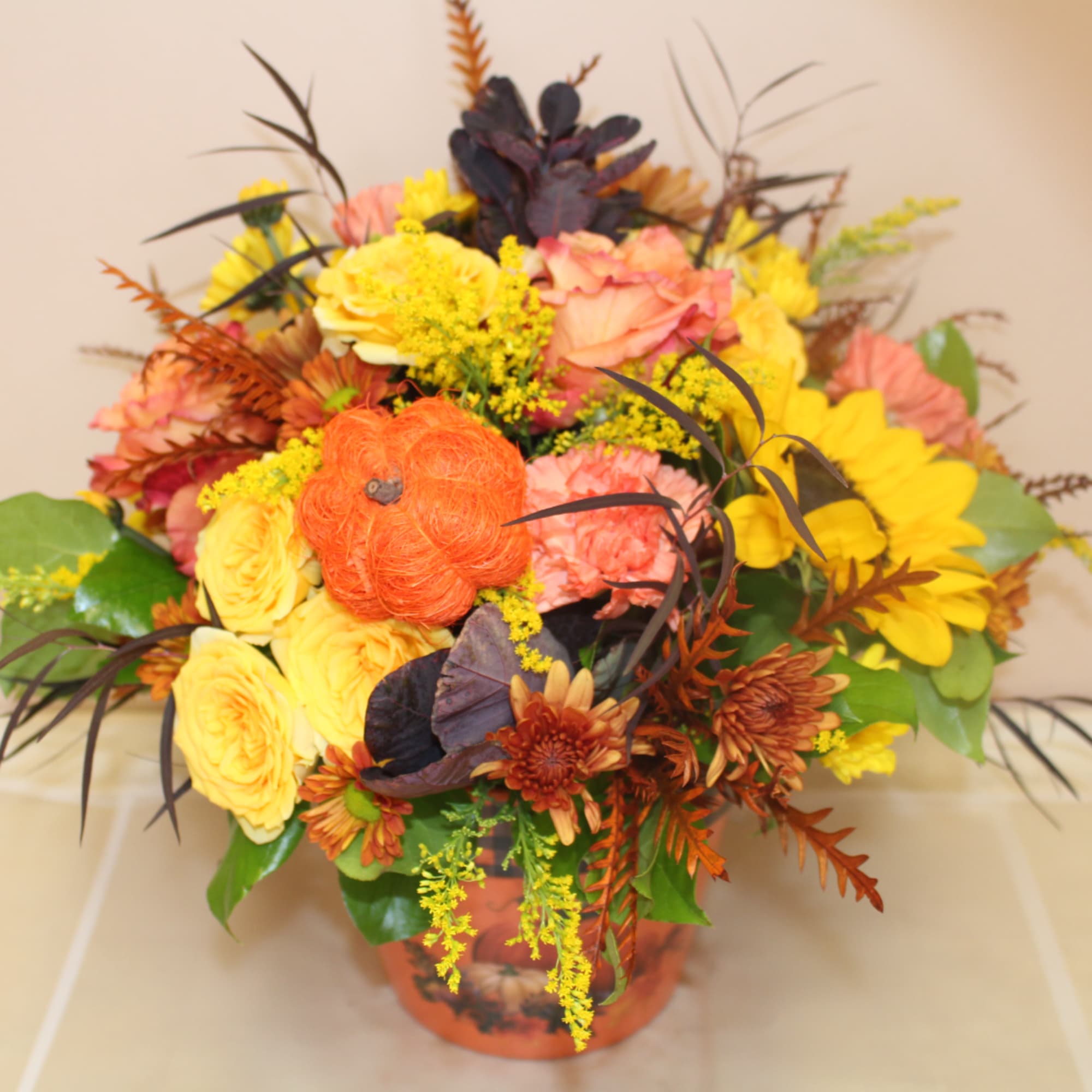 Autumn floral arrangement in an orange vase with yellow and peach blooms