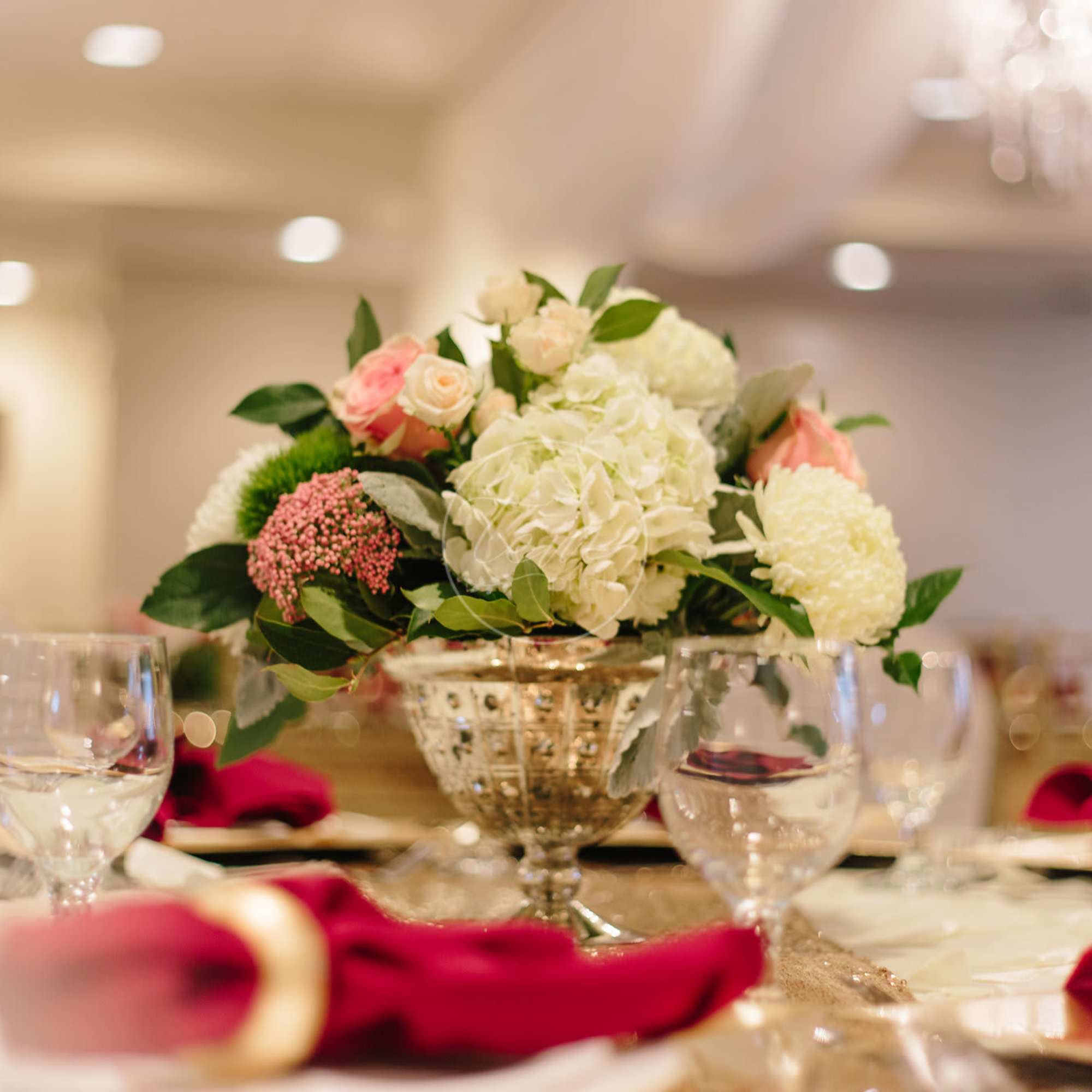 Low floral centerpiece in a gold vase with white and pink blooms