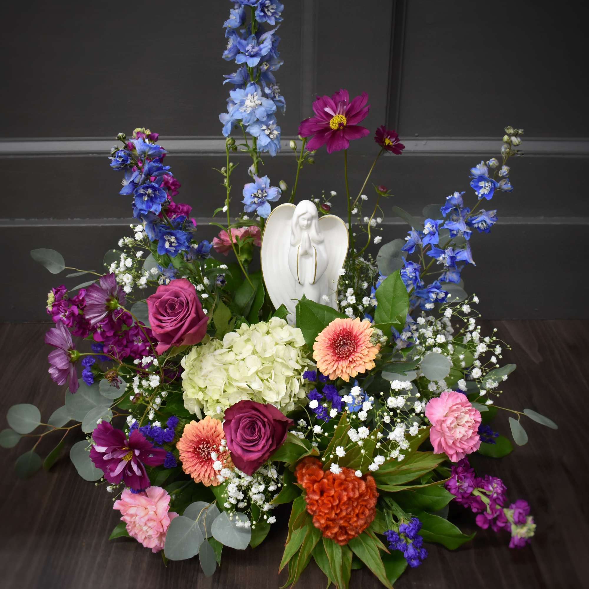 Colorful floral arrangement with roses, hydrangea, and a white angel figurine