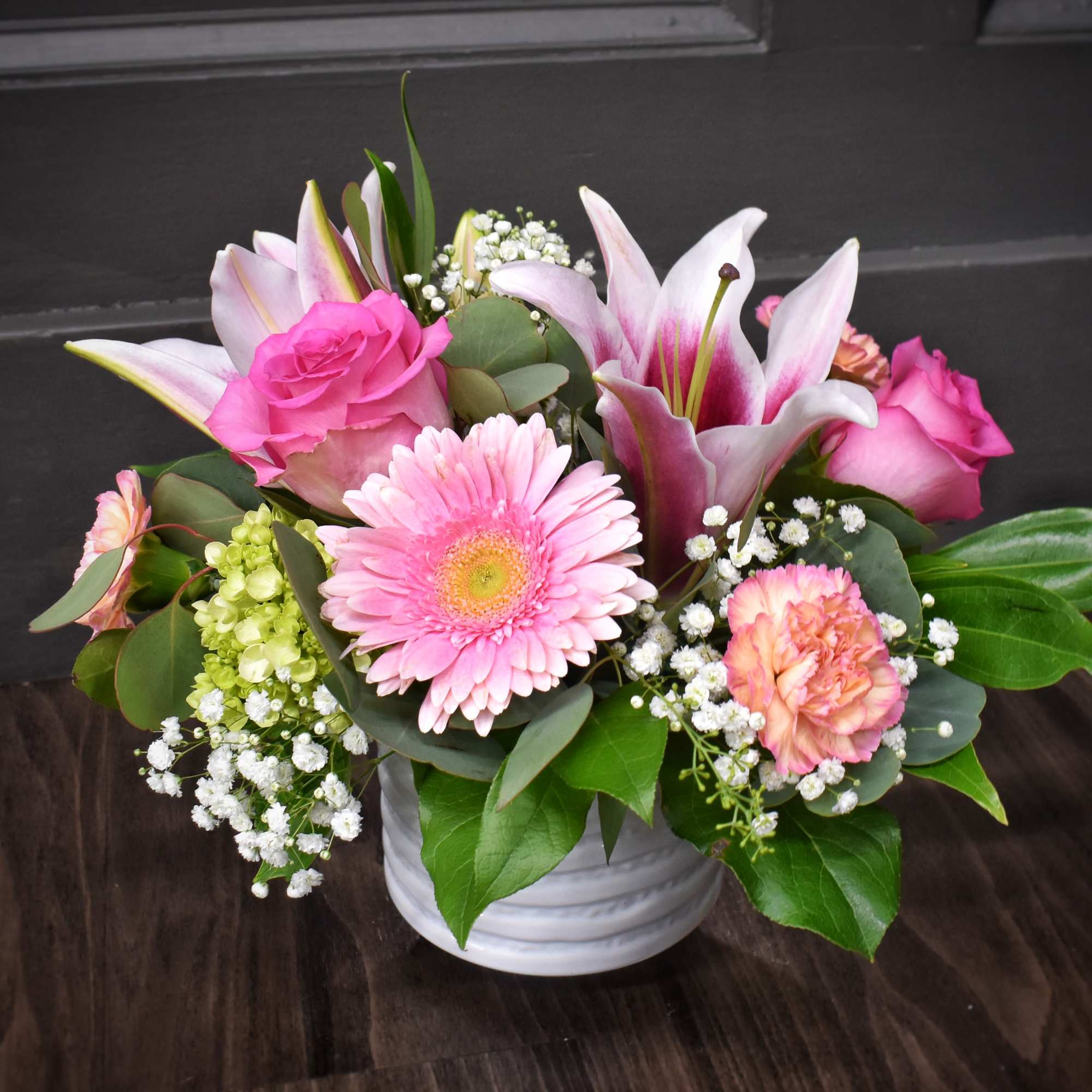 A bright cluster of pink lilies and  large pink gerbera daisies