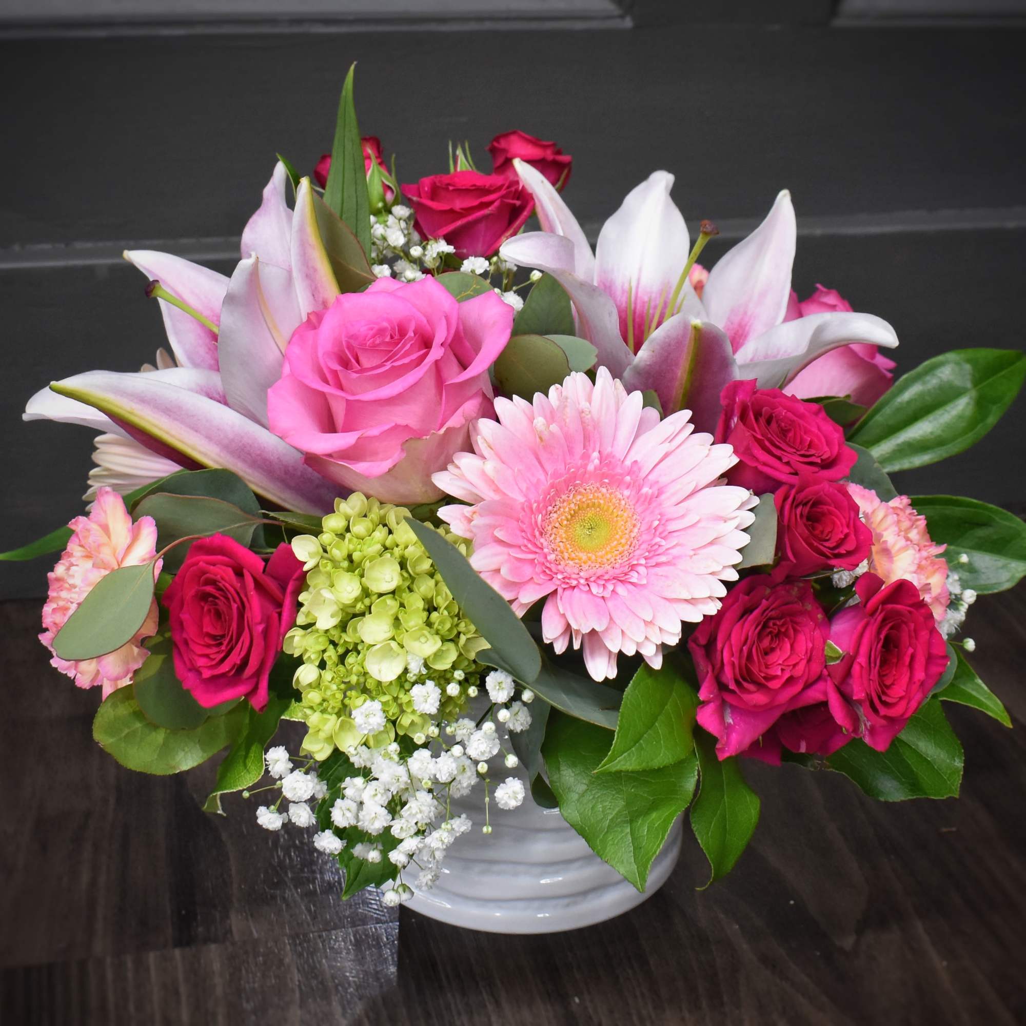 A bright cluster of pink lilies and  large pink gerbera daisies