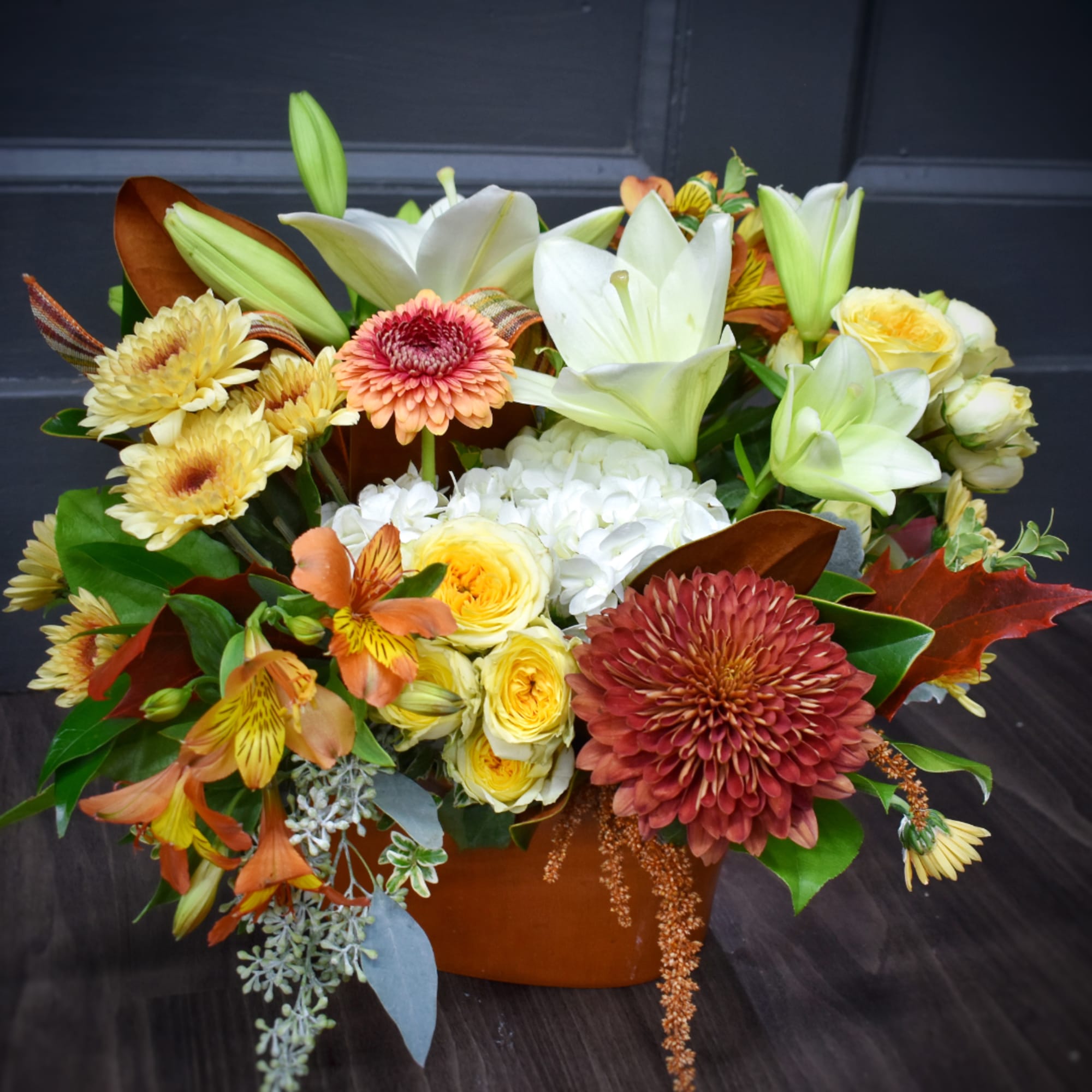 Mixed bouquet with lilies, chrysanthemums, roses, and alstroemeria in a brown container