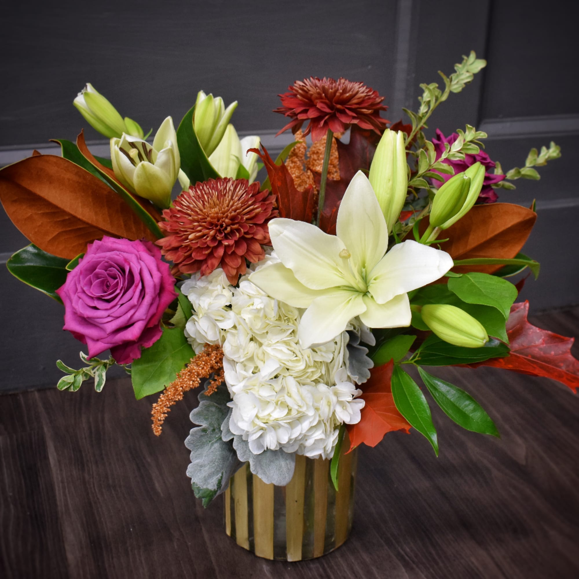 Mixed bouquet with lilies, roses, and chrysanthemums in a gold vase