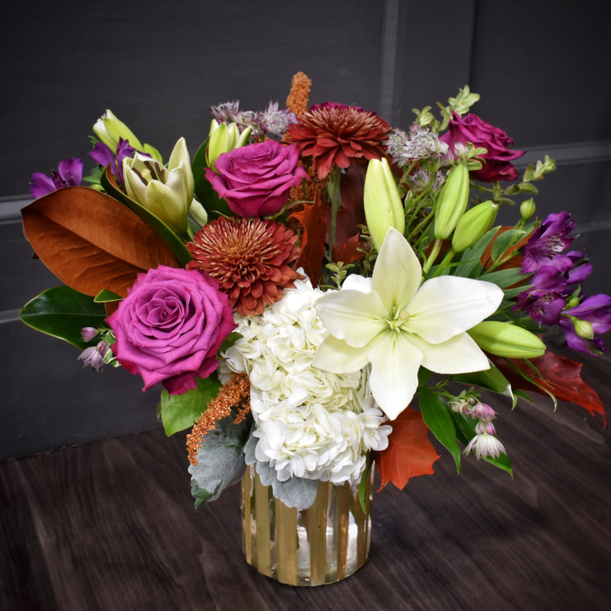 Mixed bouquet of roses, lilies, hydrangea, and chrysanthemums in a gold vase