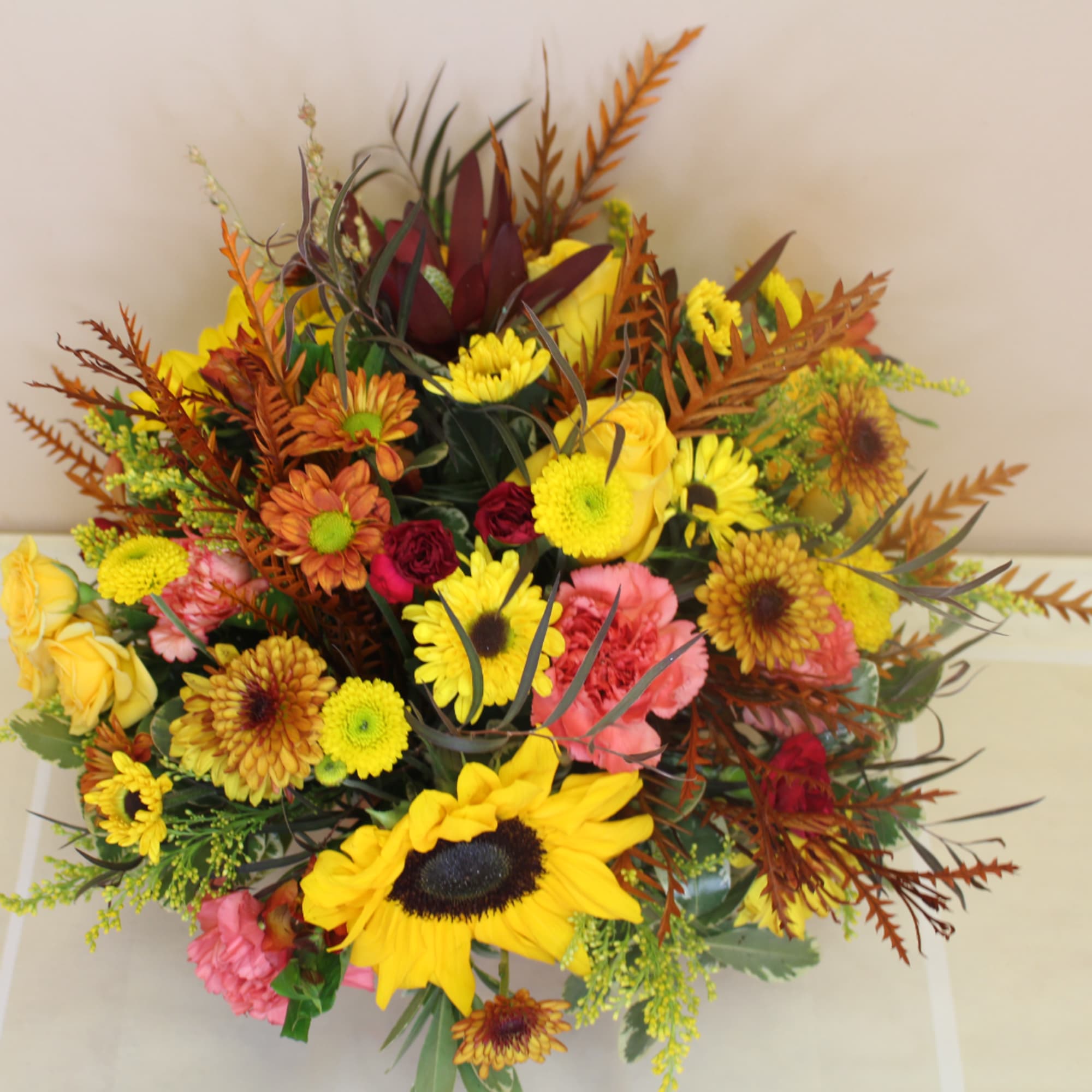 Mixed bouquet with sunflowers, mums, and roses in yellow, orange, pink, and burgundy.