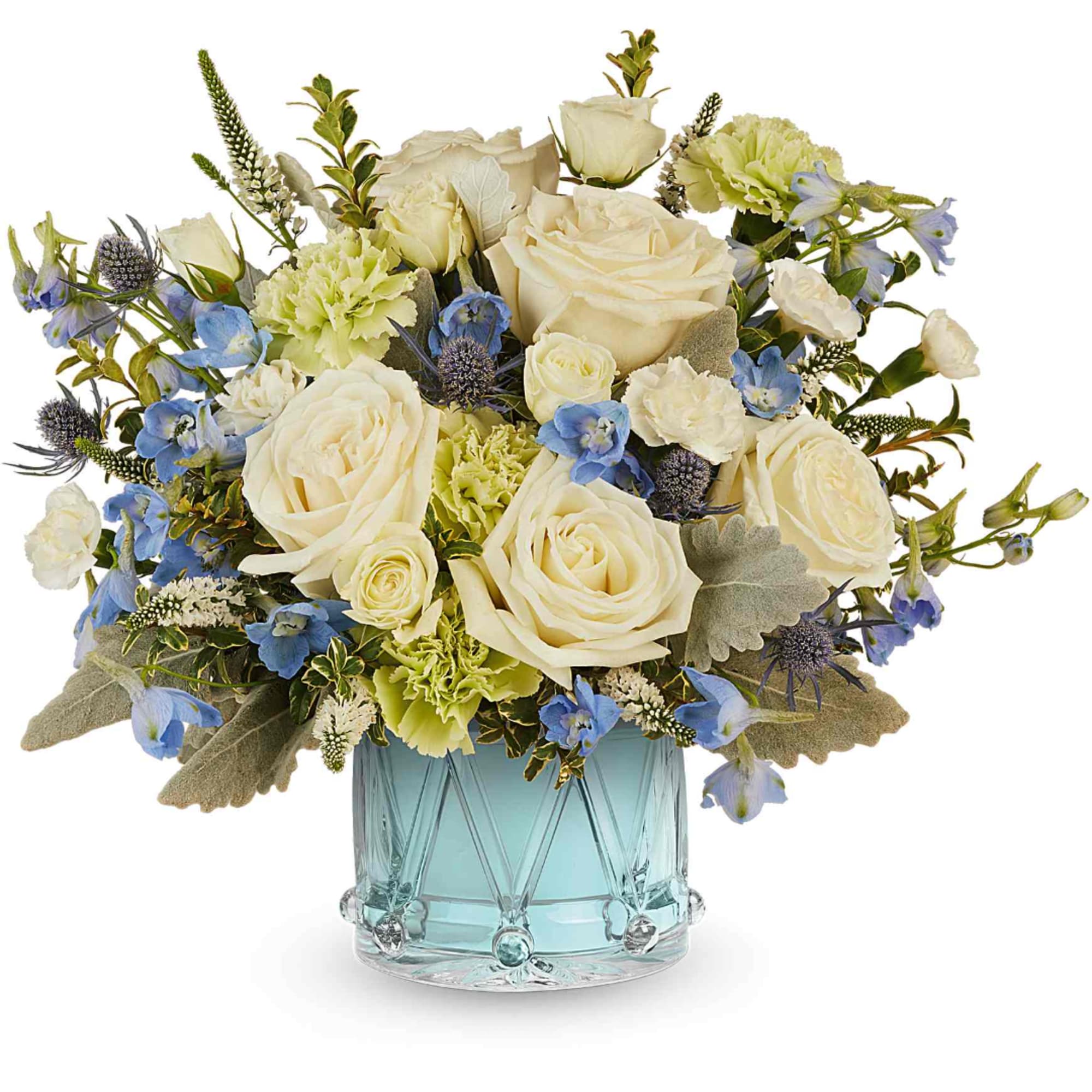 Cream roses and blue flowers arranged in a glass vase