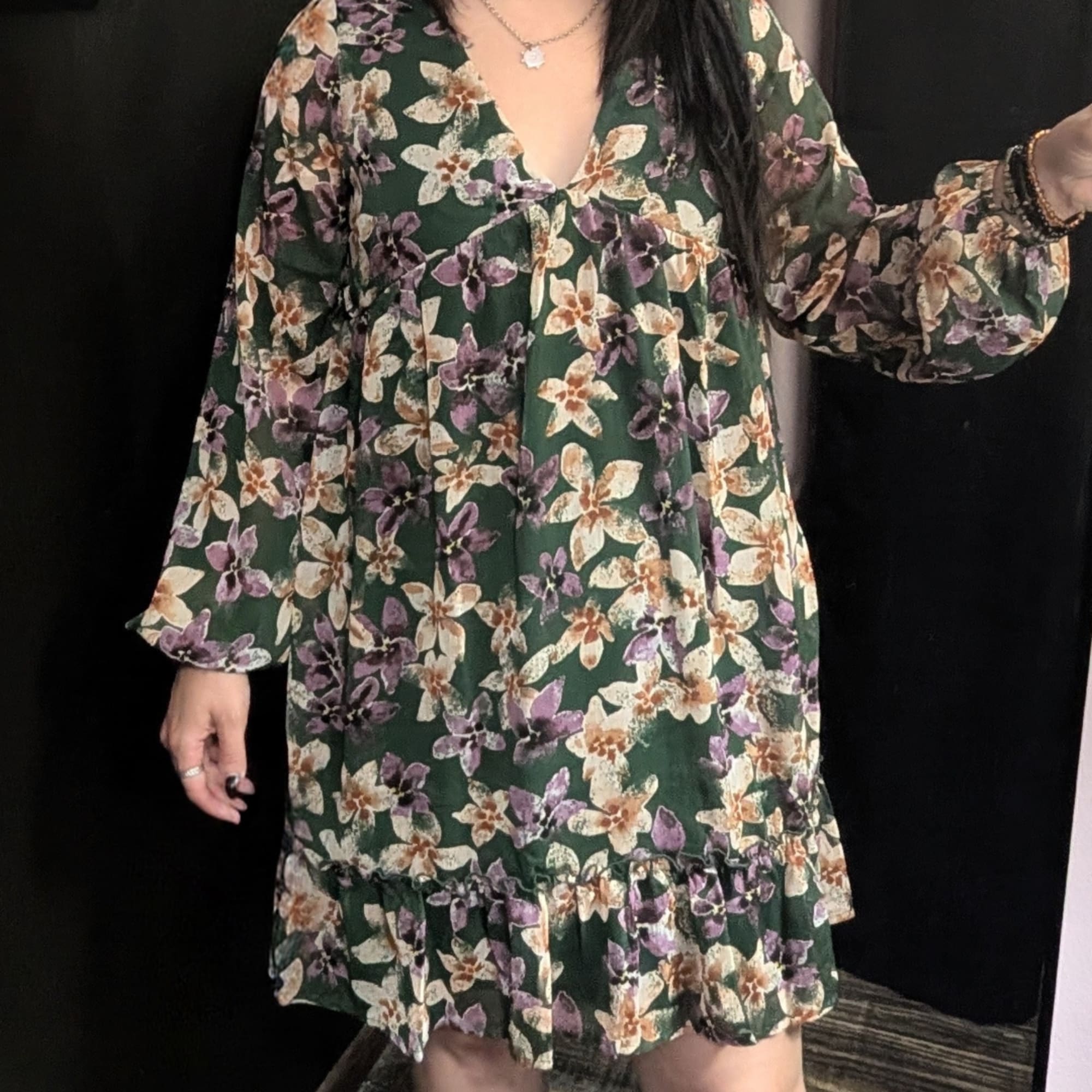 Woman wearing a dark green floral dress with long sleeves
