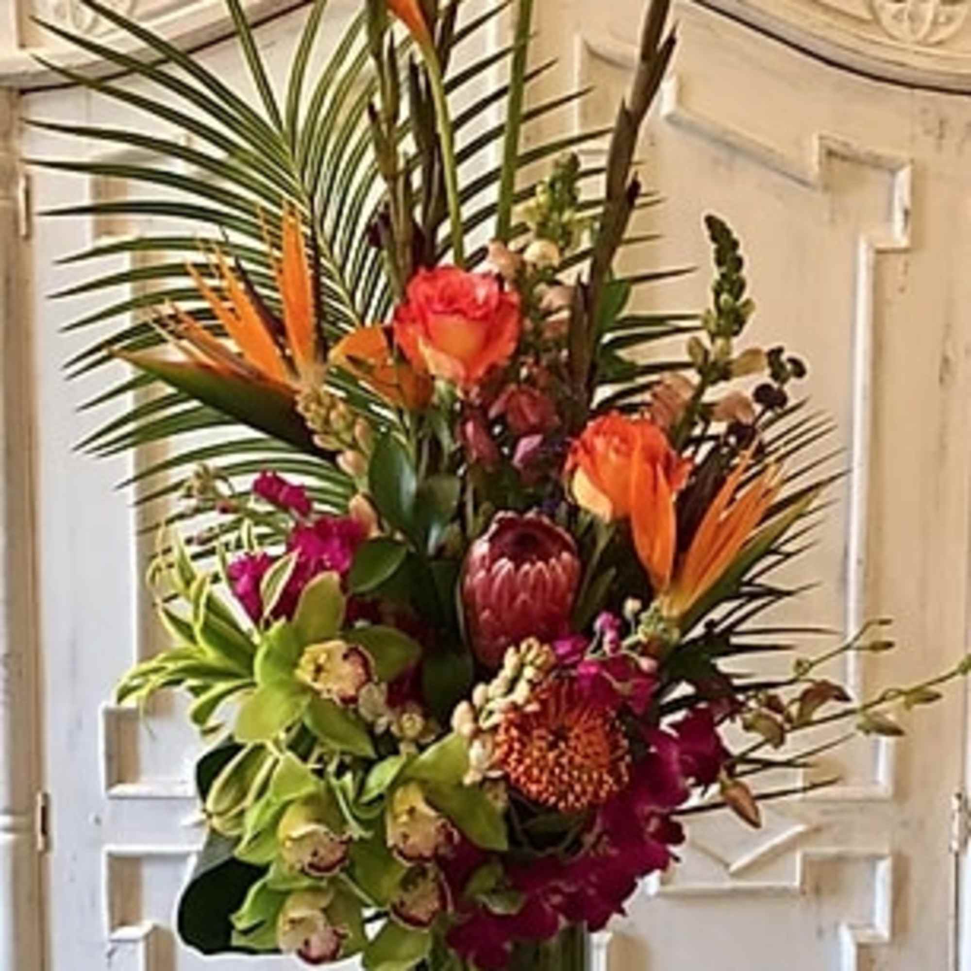 Tall tropical flower arrangement with orange birds of paradise and pink blooms