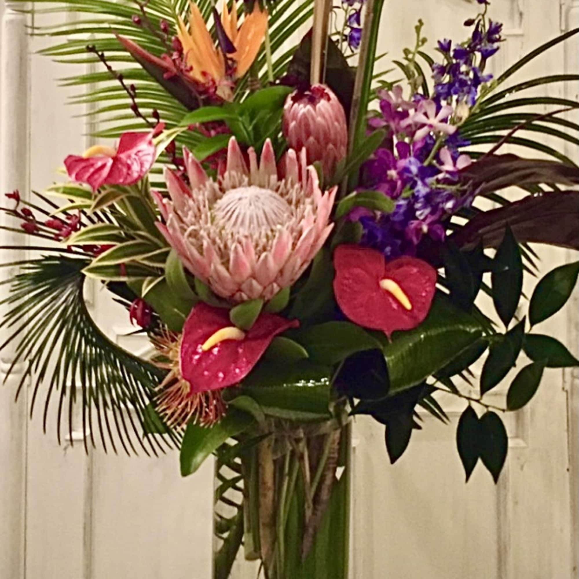 Tropical floral arrangement in a tall glass vase with pink and purple blooms