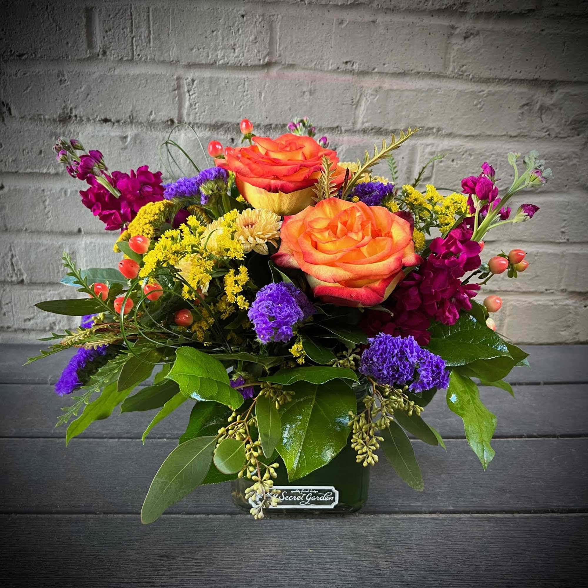 Bright mixed bouquet with orange roses in a glass vase