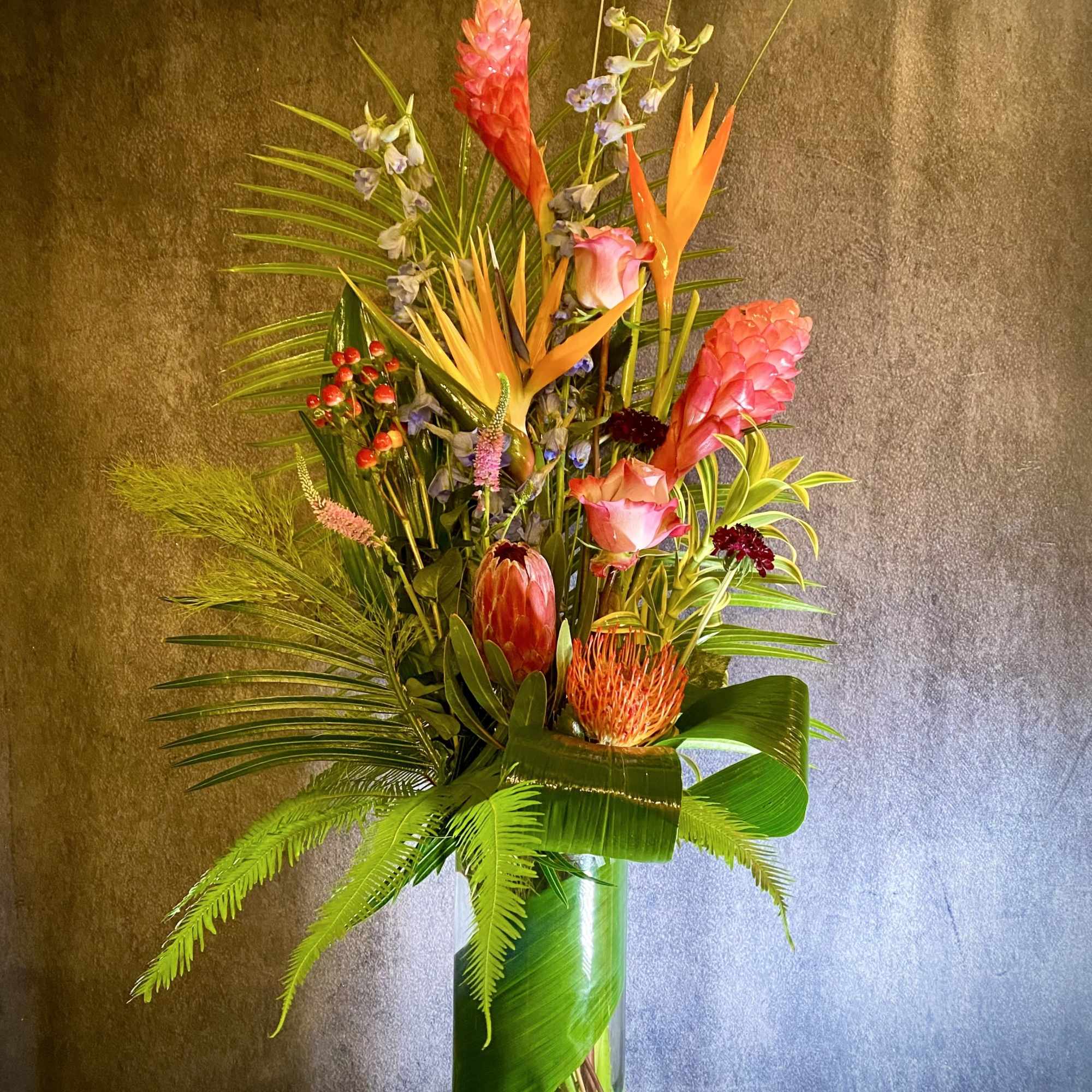 Tall tropical flower arrangement in a clear glass vase