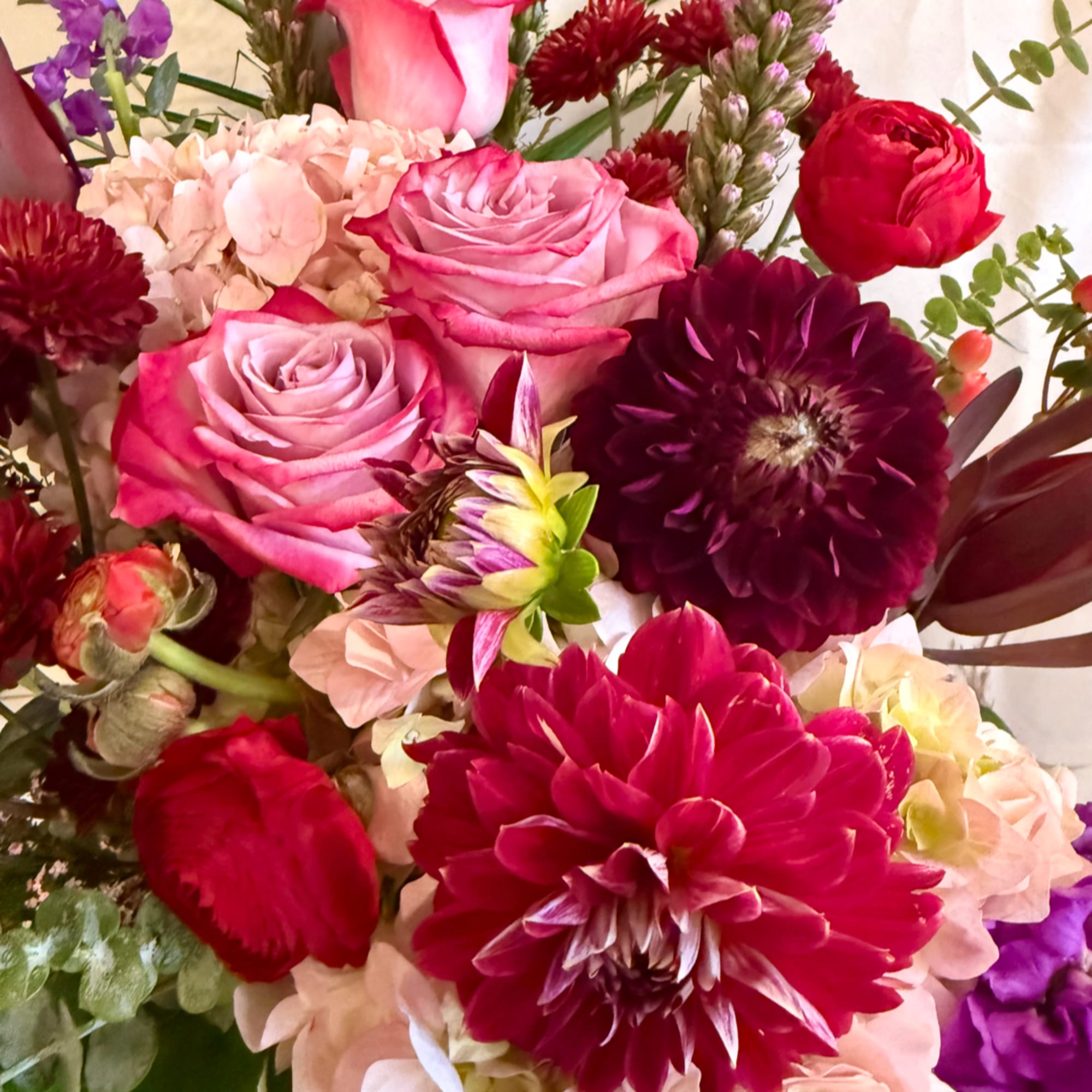 Mixed bouquet with pink roses, hydrangeas, and deep red blooms