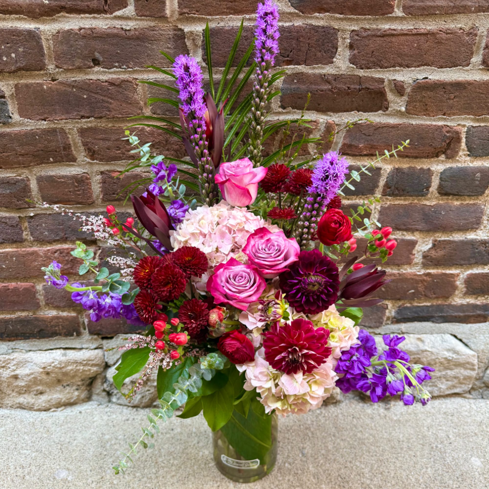 Mixed bouquet in a glass vase with pink roses and purple flowers