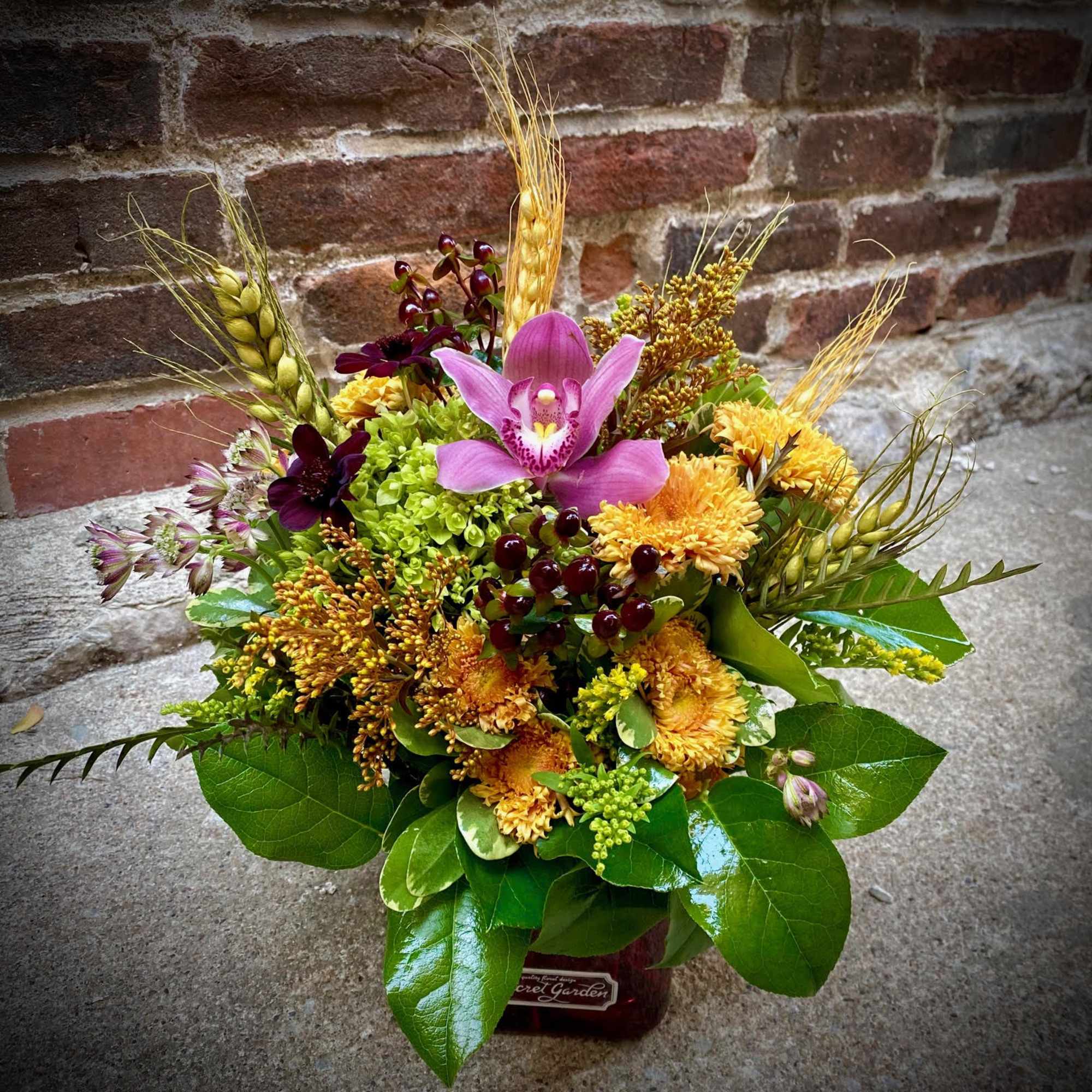 Mixed bouquet with a pink orchid and yellow flowers in a vase