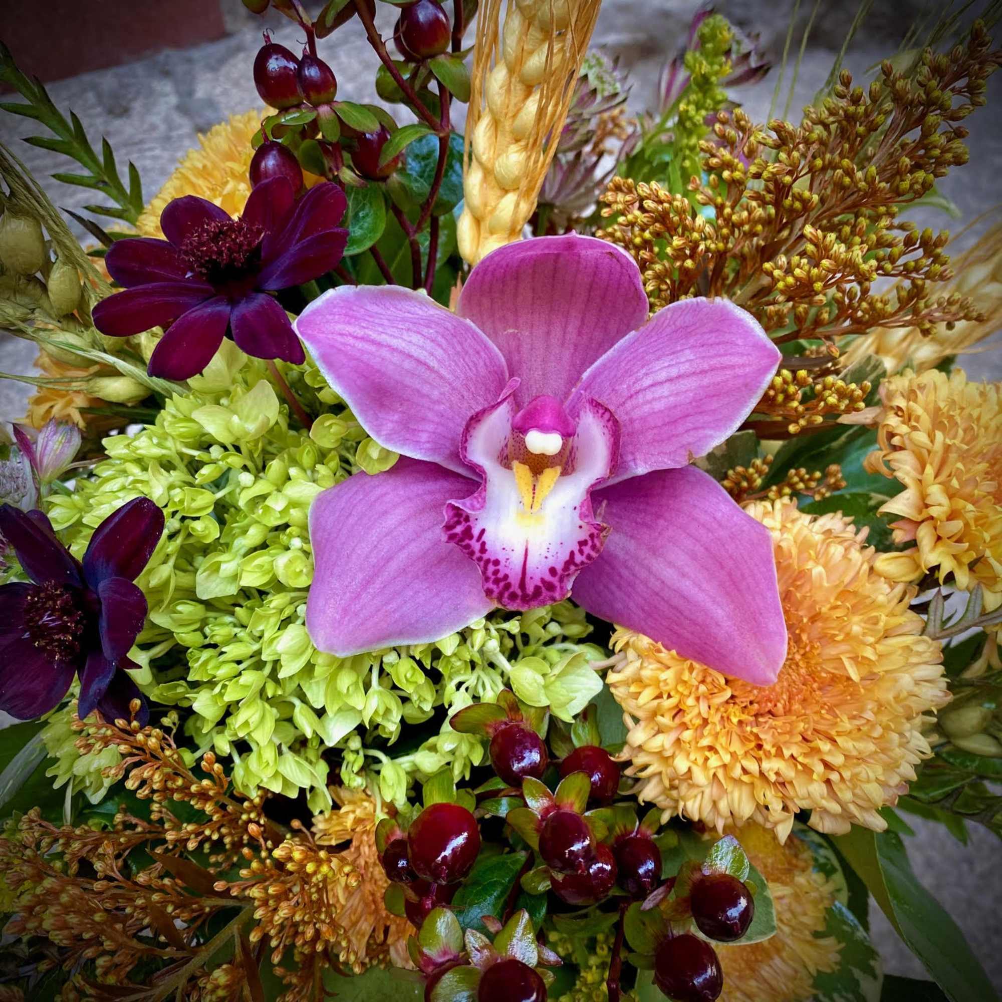 Mixed bouquet with a pink orchid, green hydrangea, and yellow blooms