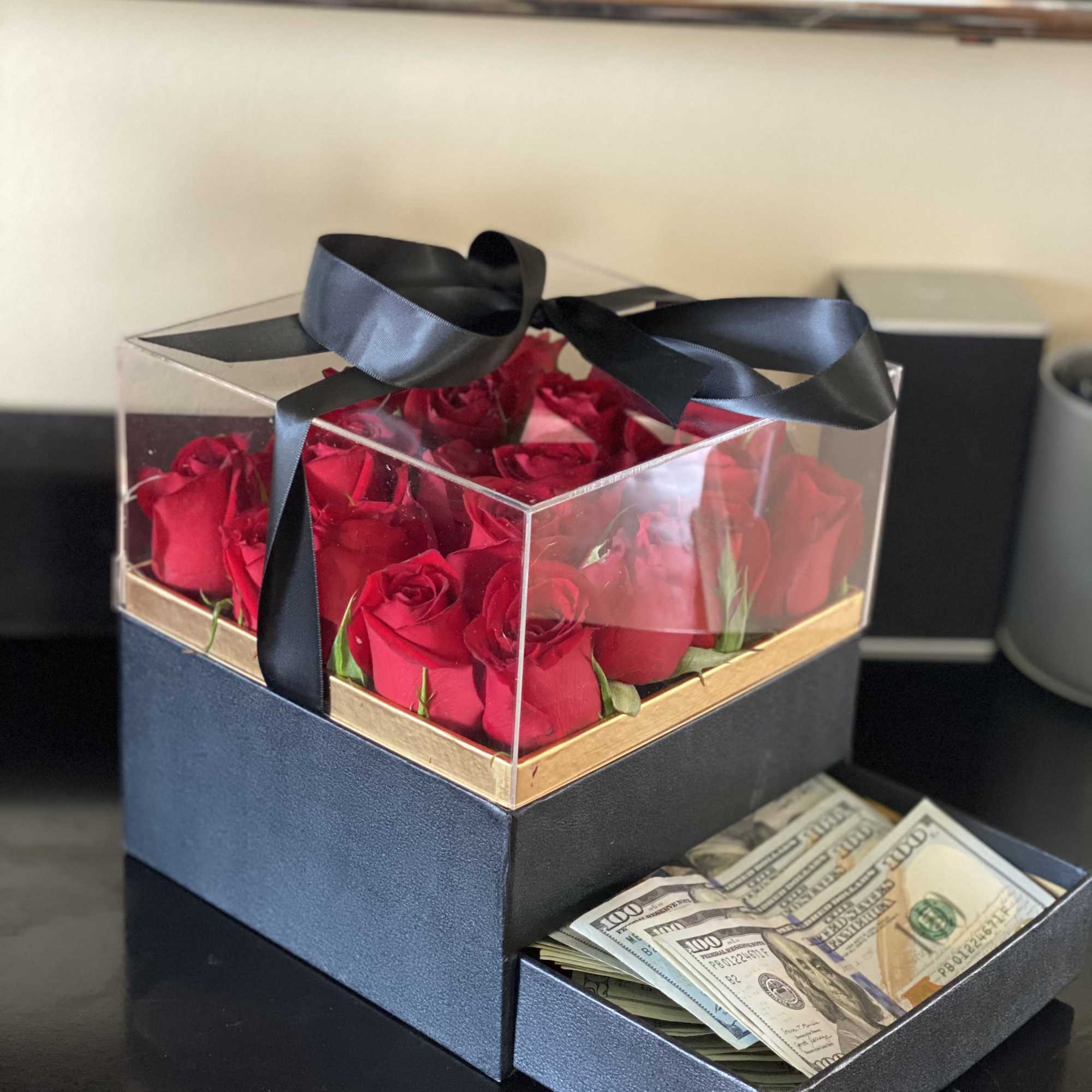 Box of red roses with a ribbon and a drawer of cash