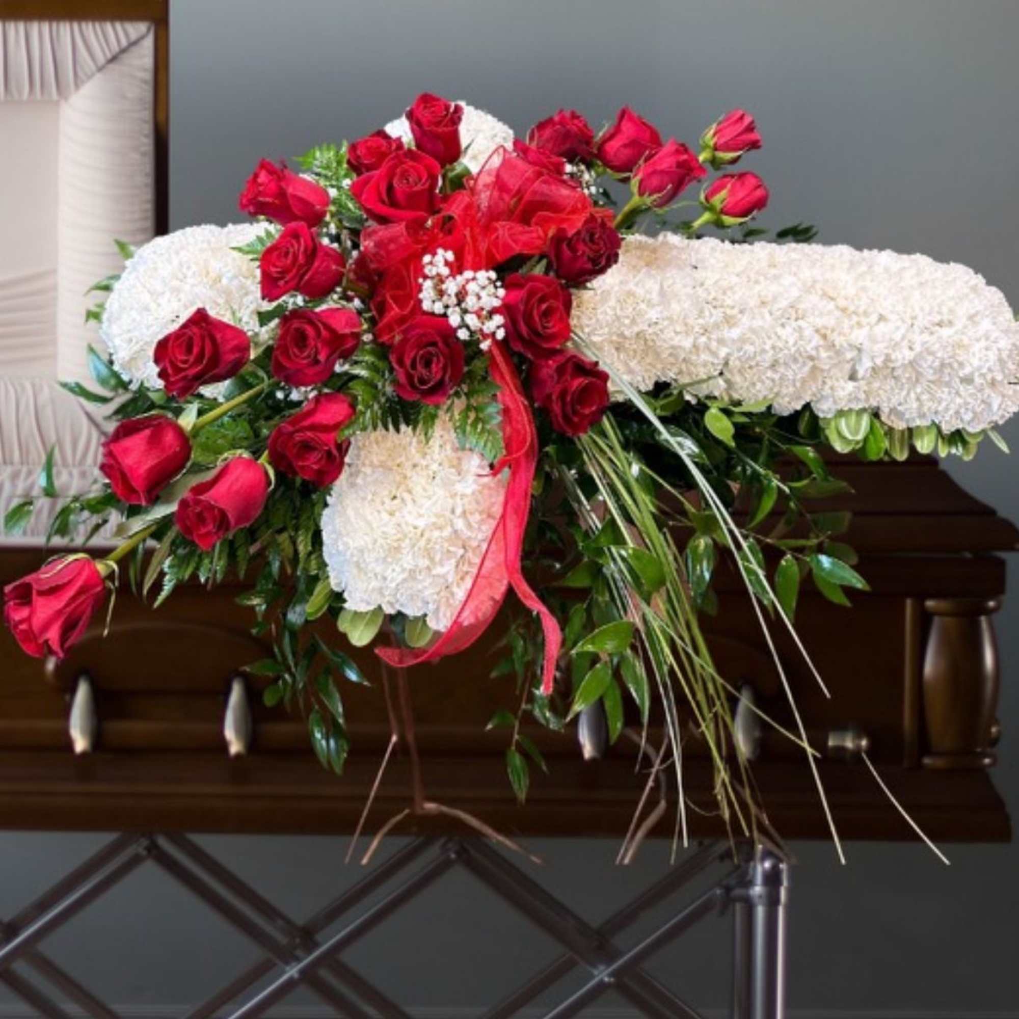 Red roses and white floral spray arranged on a stand