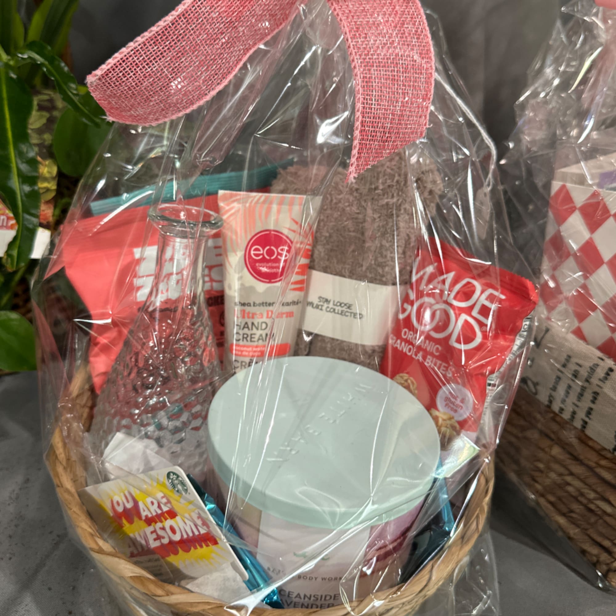 Gift basket with skincare, snacks, and a small bottle wrapped in clear cellophane