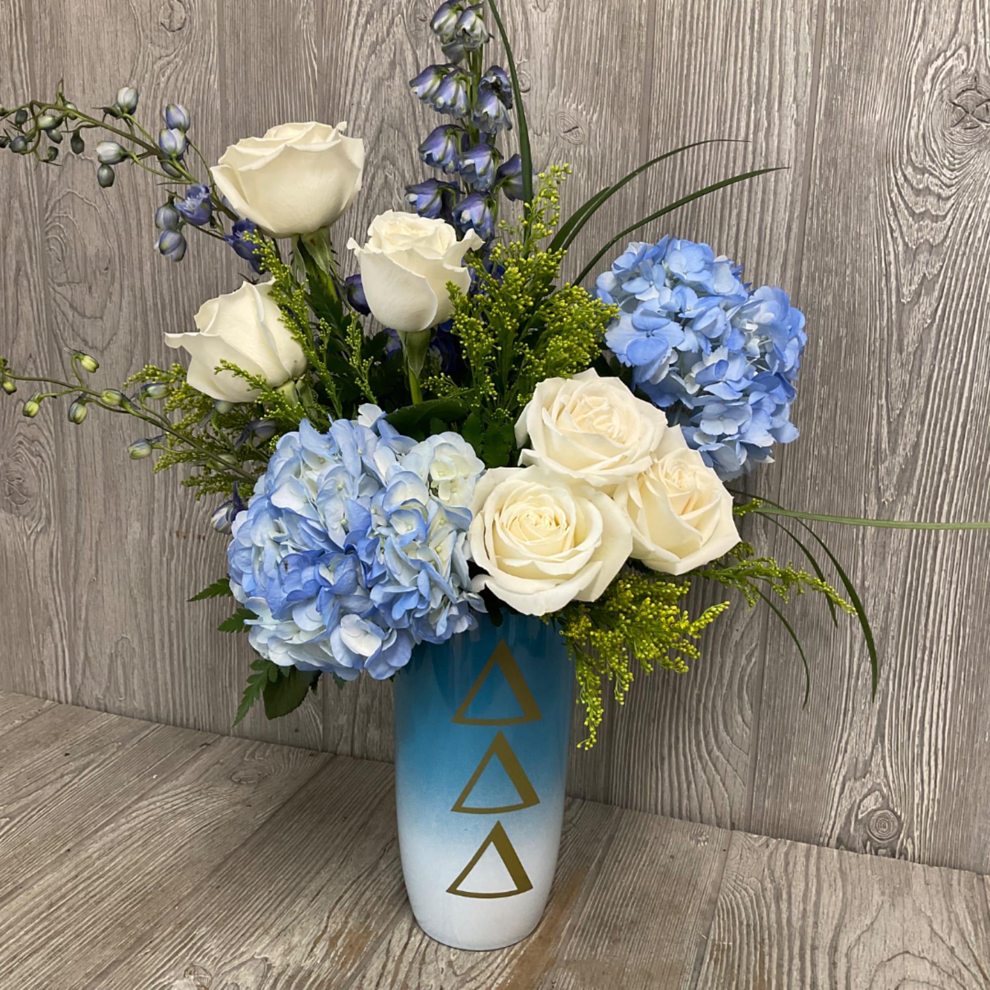 White roses and blue hydrangeas in a tall blue vase