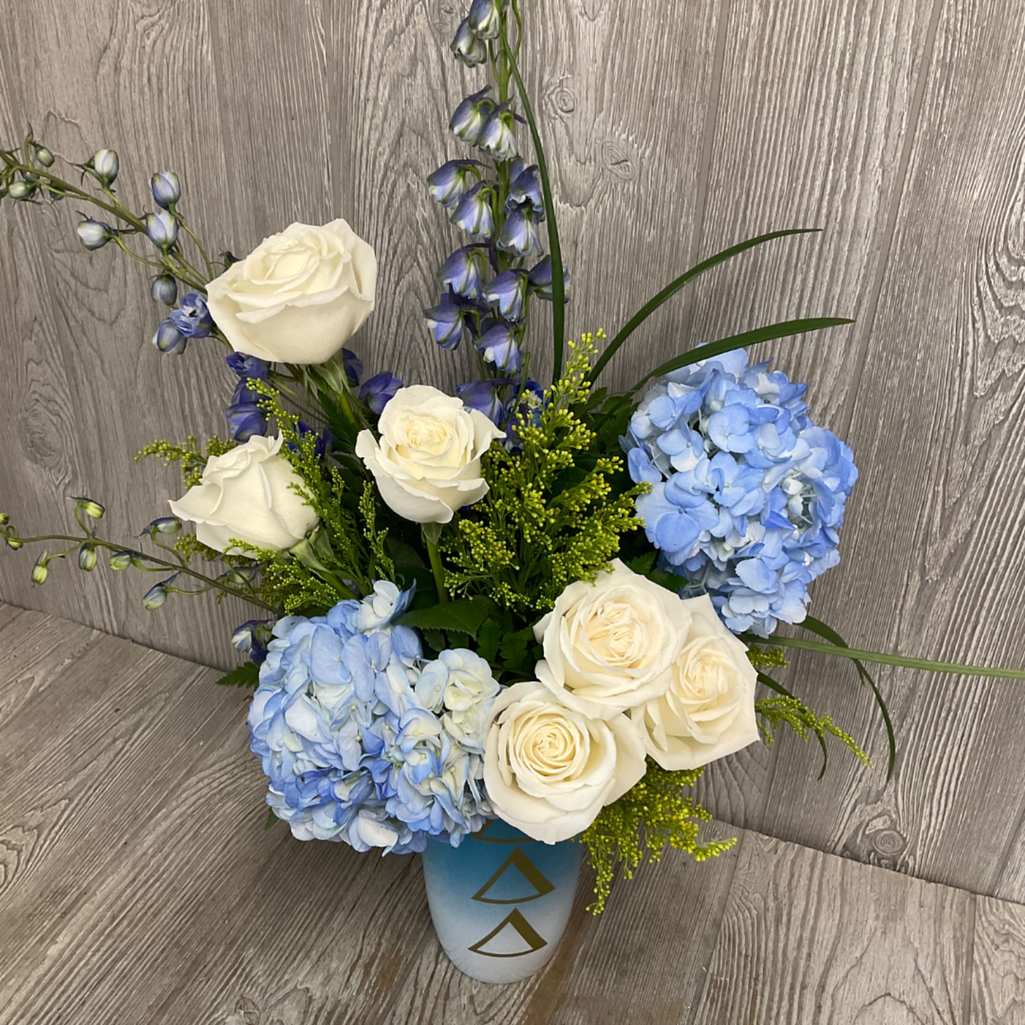 White roses and blue hydrangeas in a blue vase