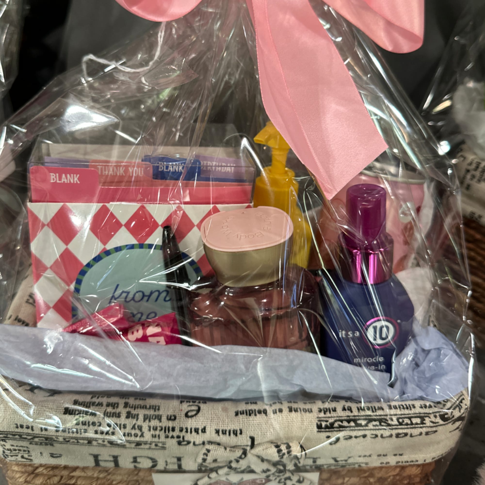 Gift basket with beauty items wrapped in clear cellophane and a pink bow