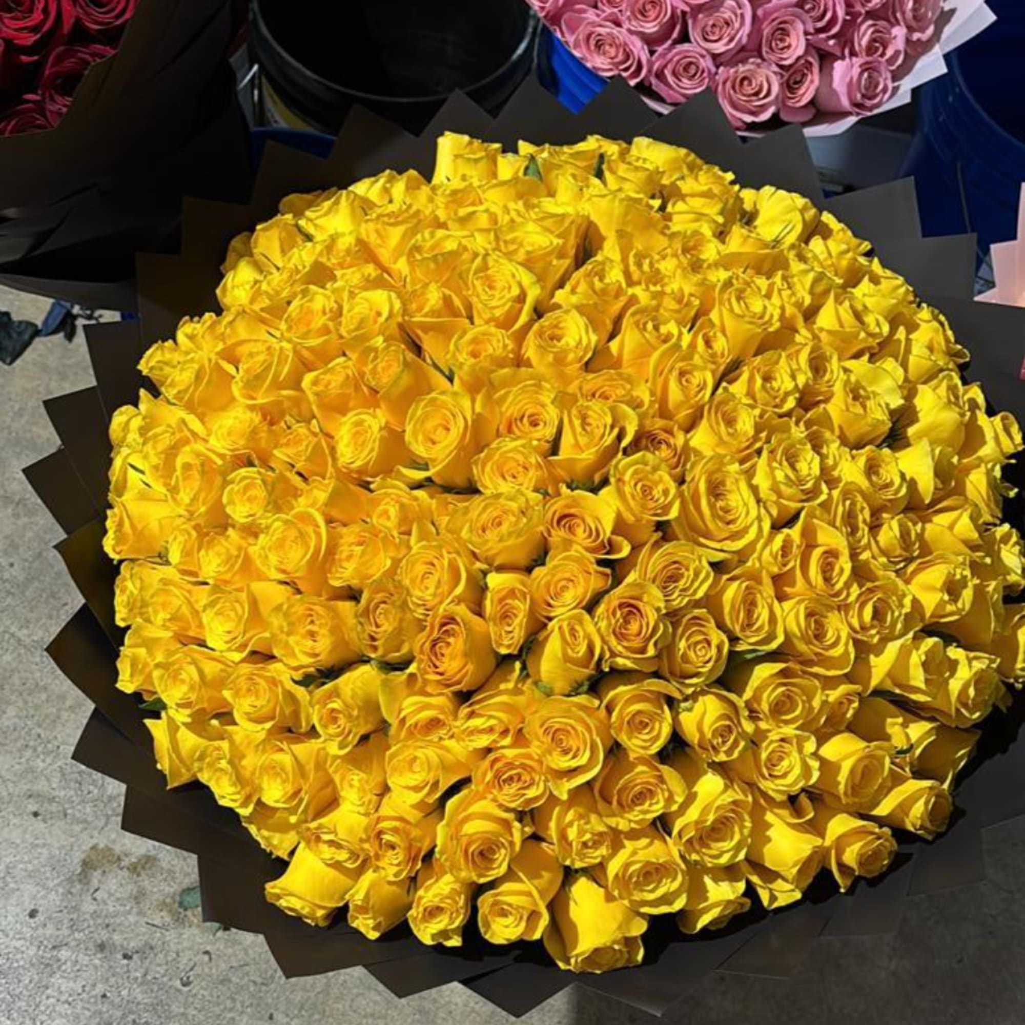 Large bouquet of yellow roses wrapped in dark paper