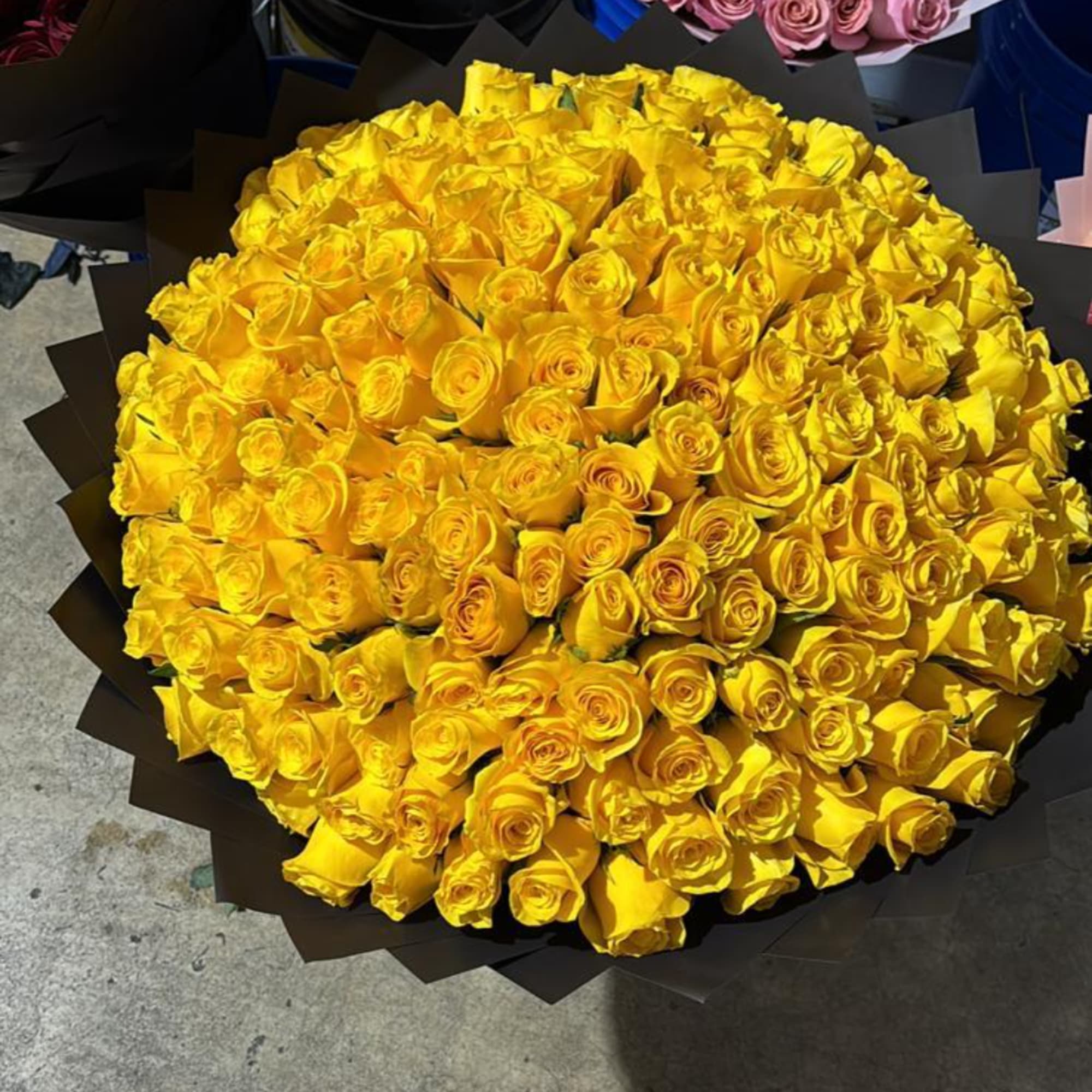 Large bouquet of yellow roses wrapped in dark paper