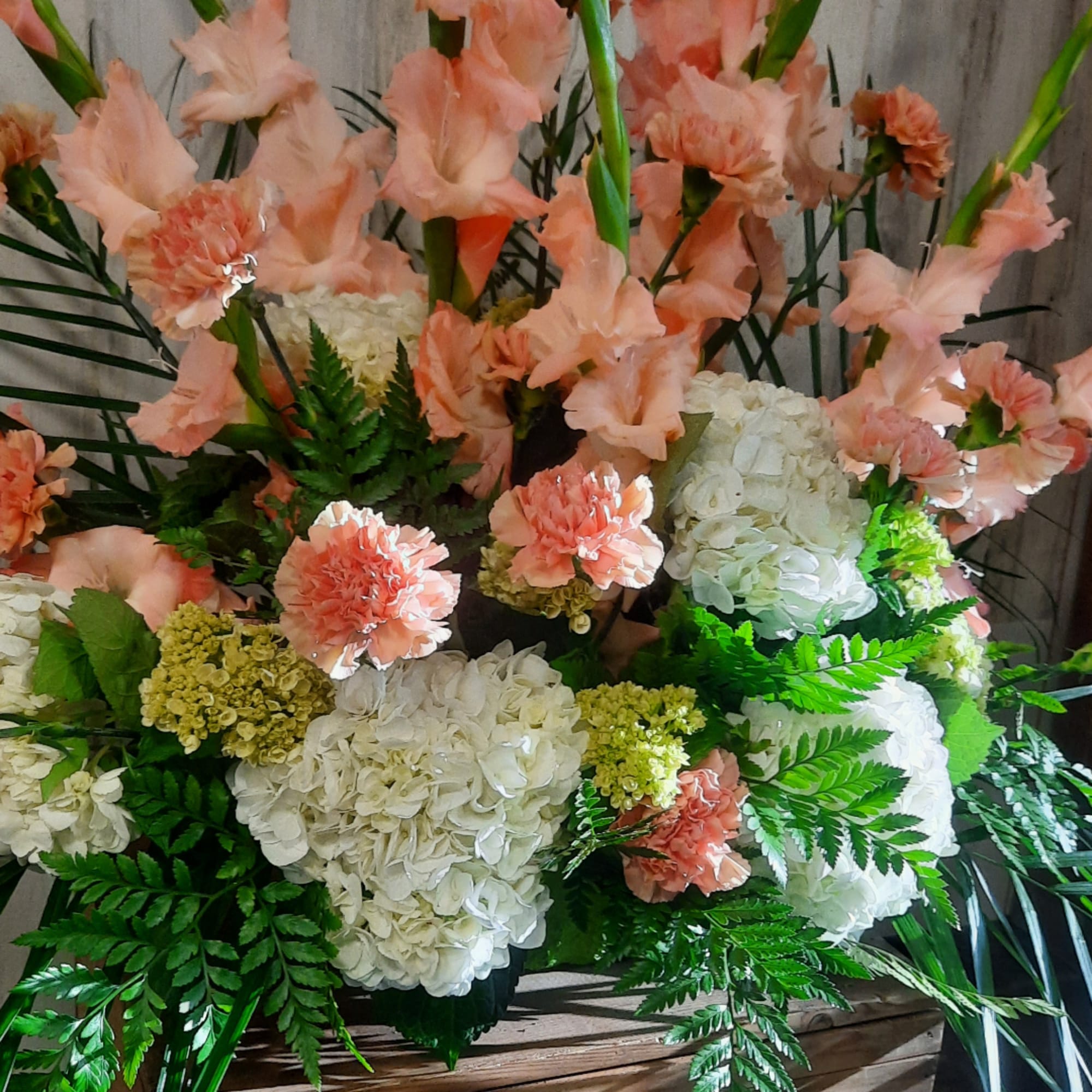 Peach carnations and white hydrangeas arranged with fern foliage
